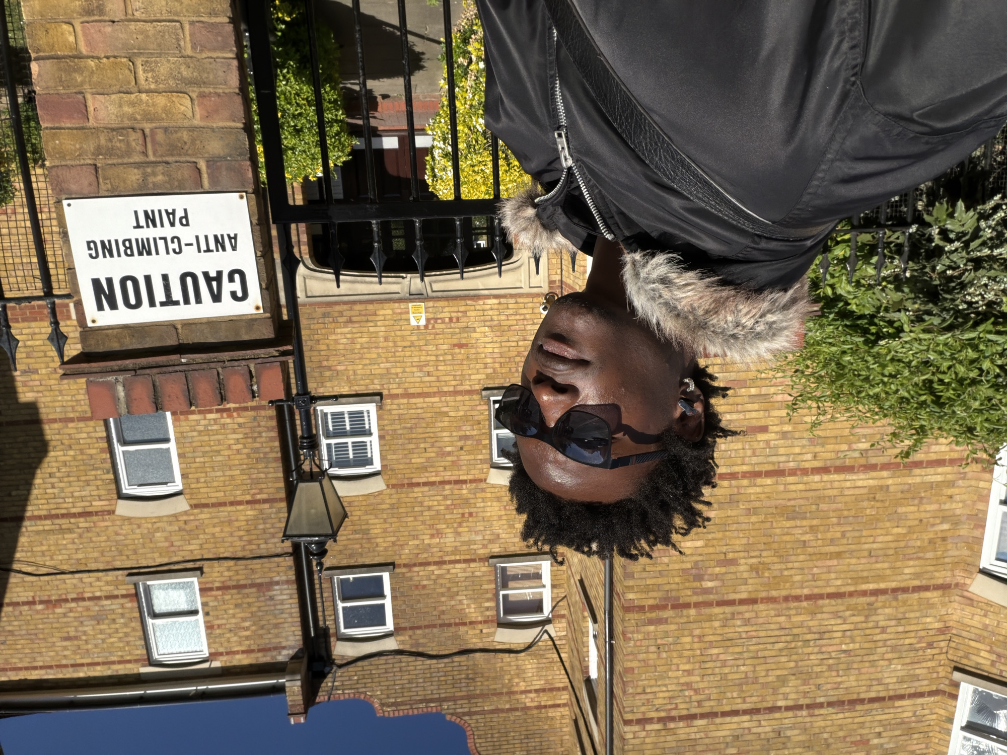 Man in fur-trimmed jacket photographed outside London brick building