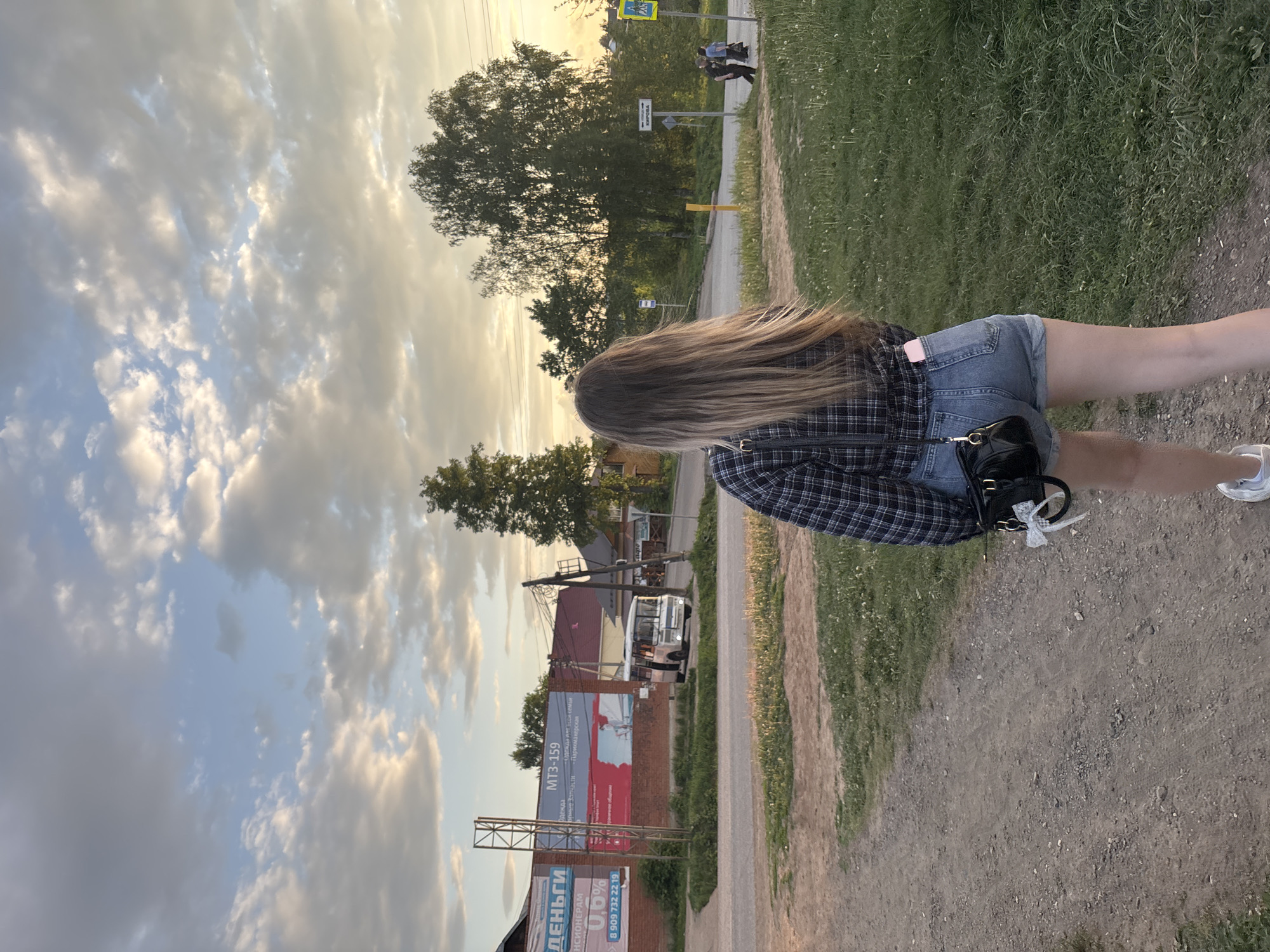 Woman walks dirt path at sunset in rural Russia