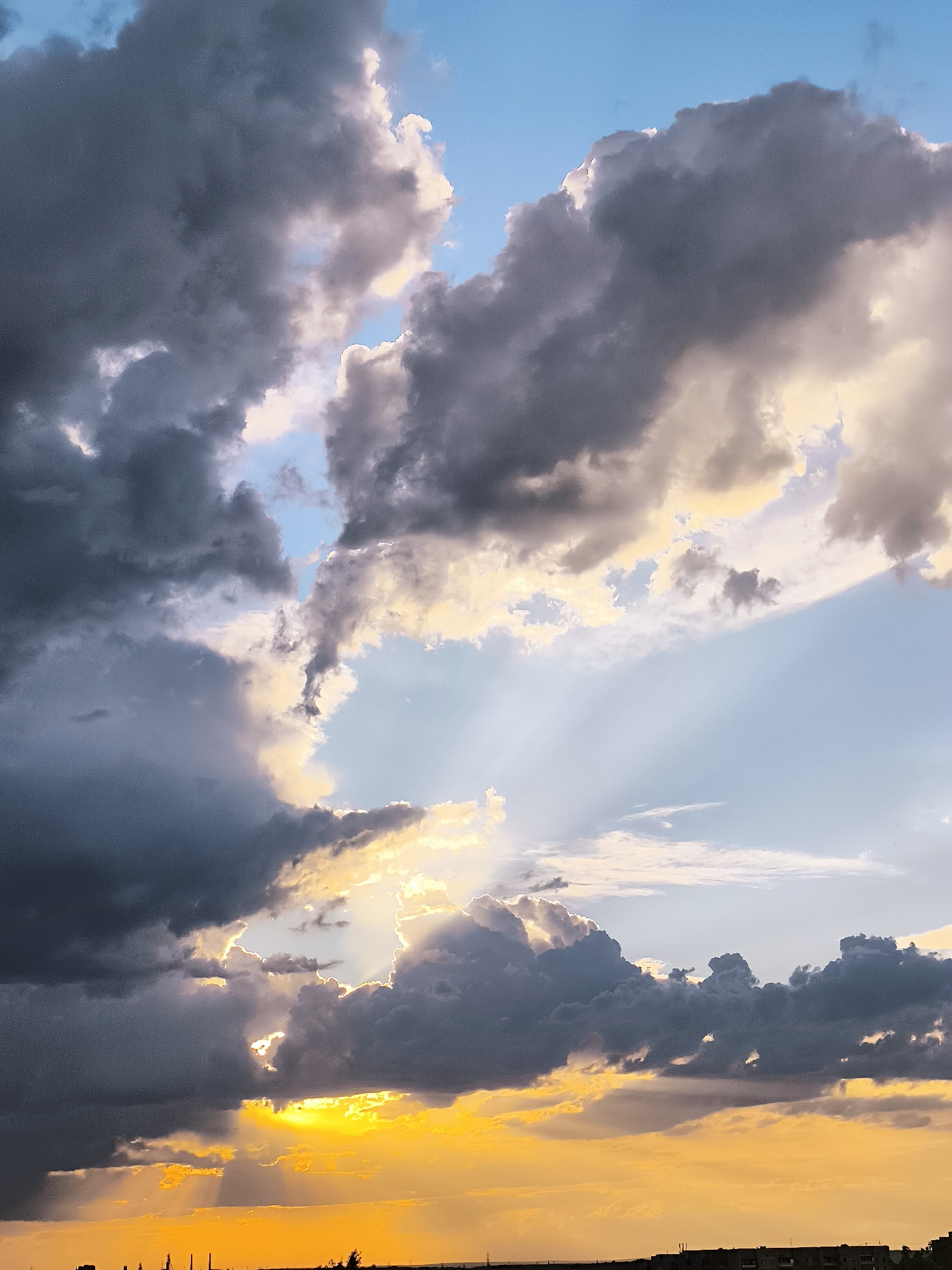Storm clouds and golden light over Qarağandı at sunset