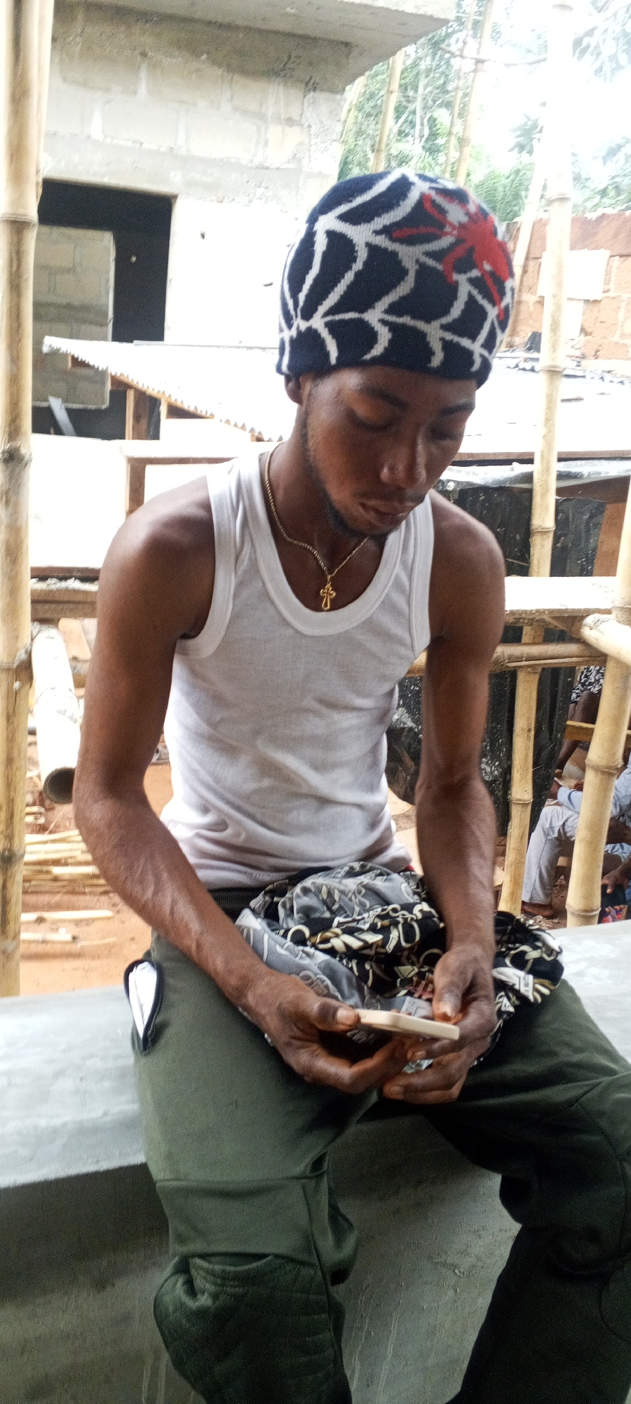 Man in tank top examines rectangular object outdoors