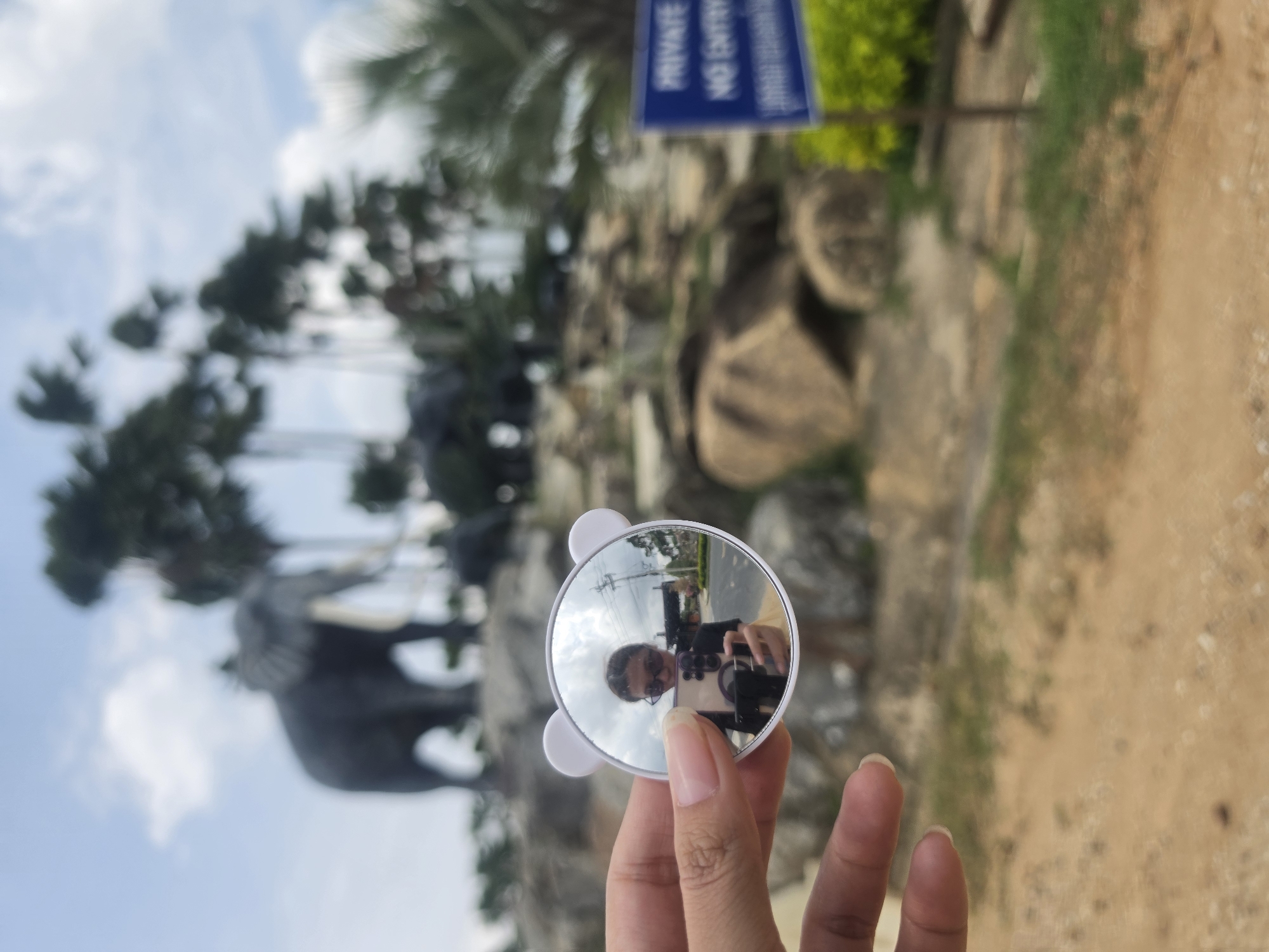 Tourist photographs elephant statues at Thai temple using novelty mirror