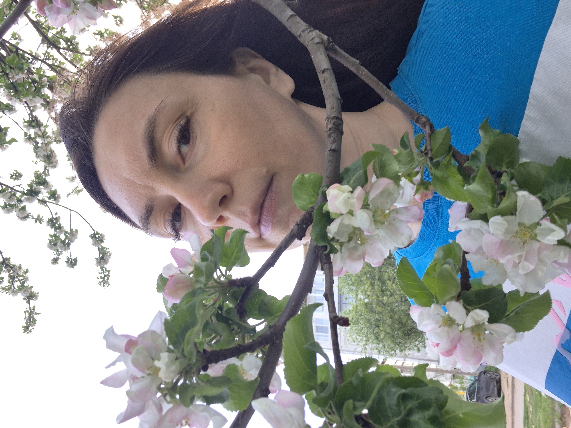 Woman poses with flowering tree blossoms in urban setting