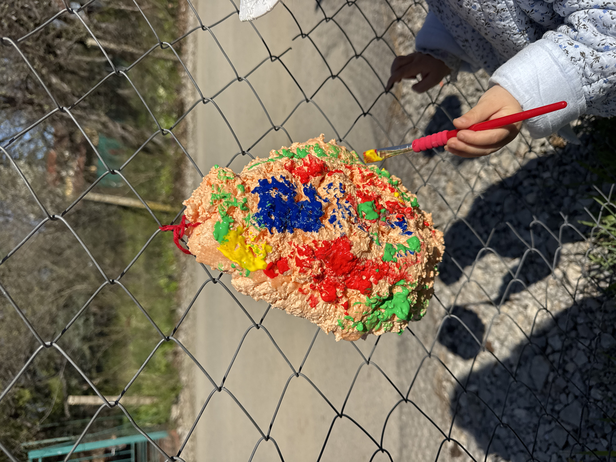 Child paints colorful artwork on fence in Sofia
