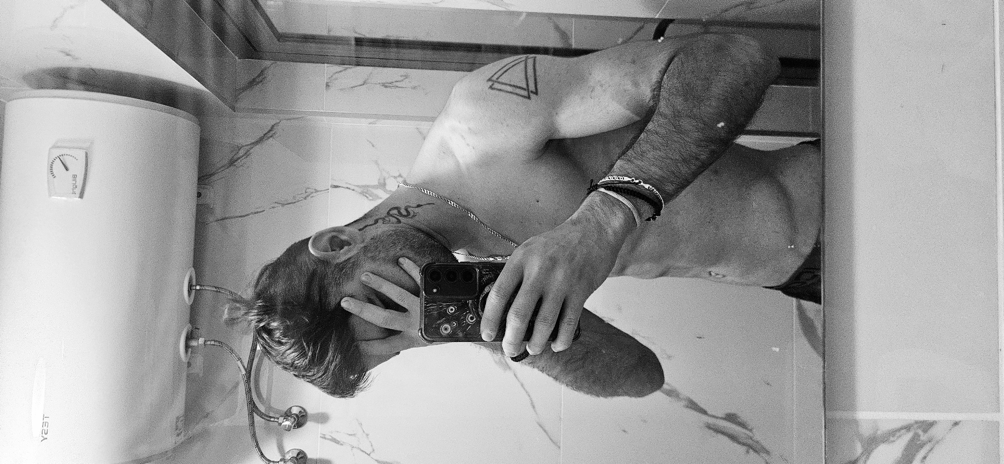 Tattooed person takes bathroom mirror selfies in Plovdiv