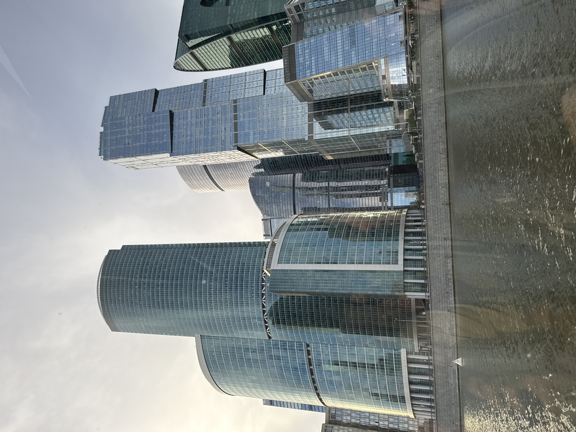 Moscow City towers rise along the Moskva River on a grey afternoon.