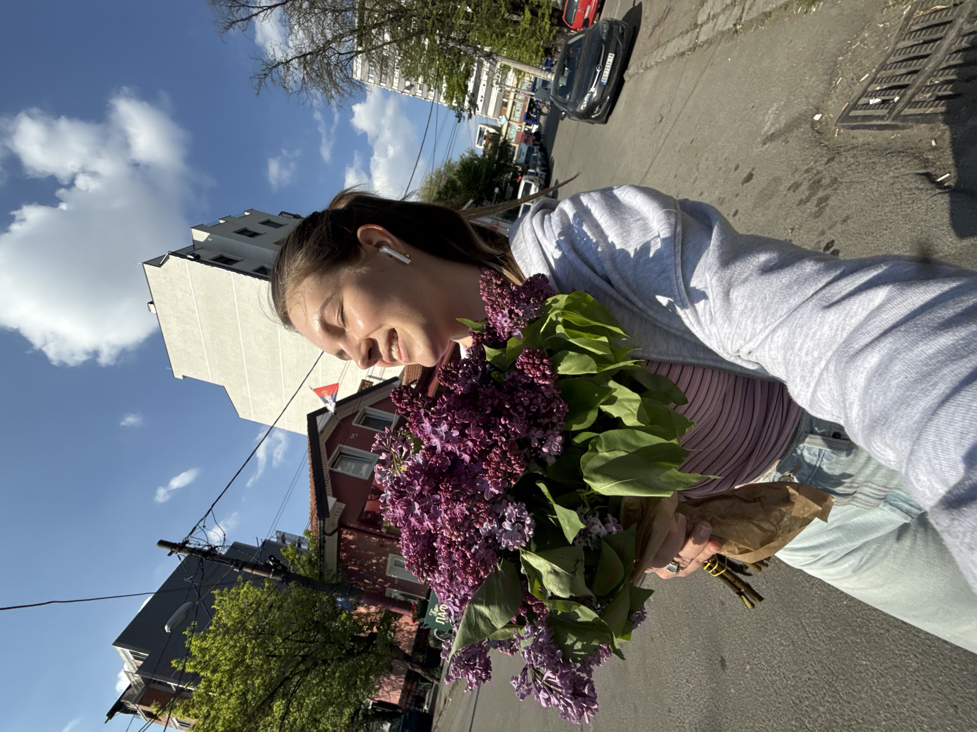 Woman poses with purple lilac bouquet on Belgrade street