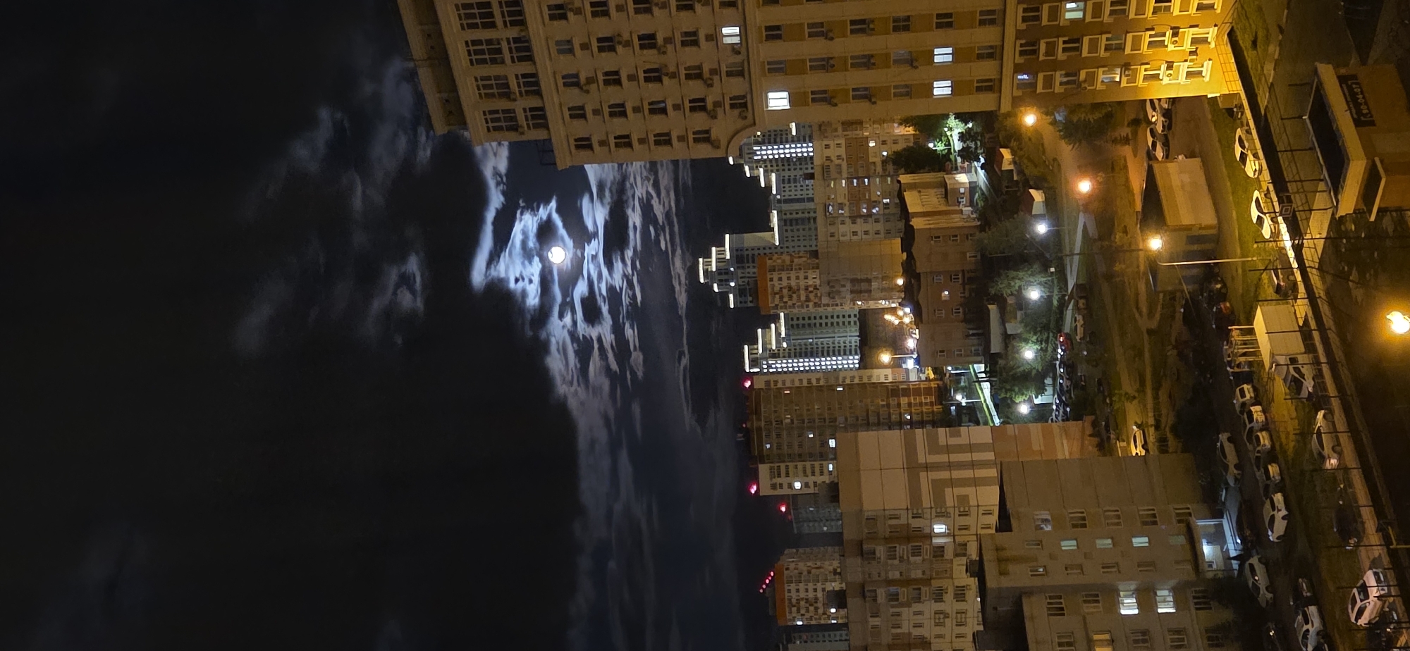 Nighttime cityscape observed from elevated position, illuminated buildings visible