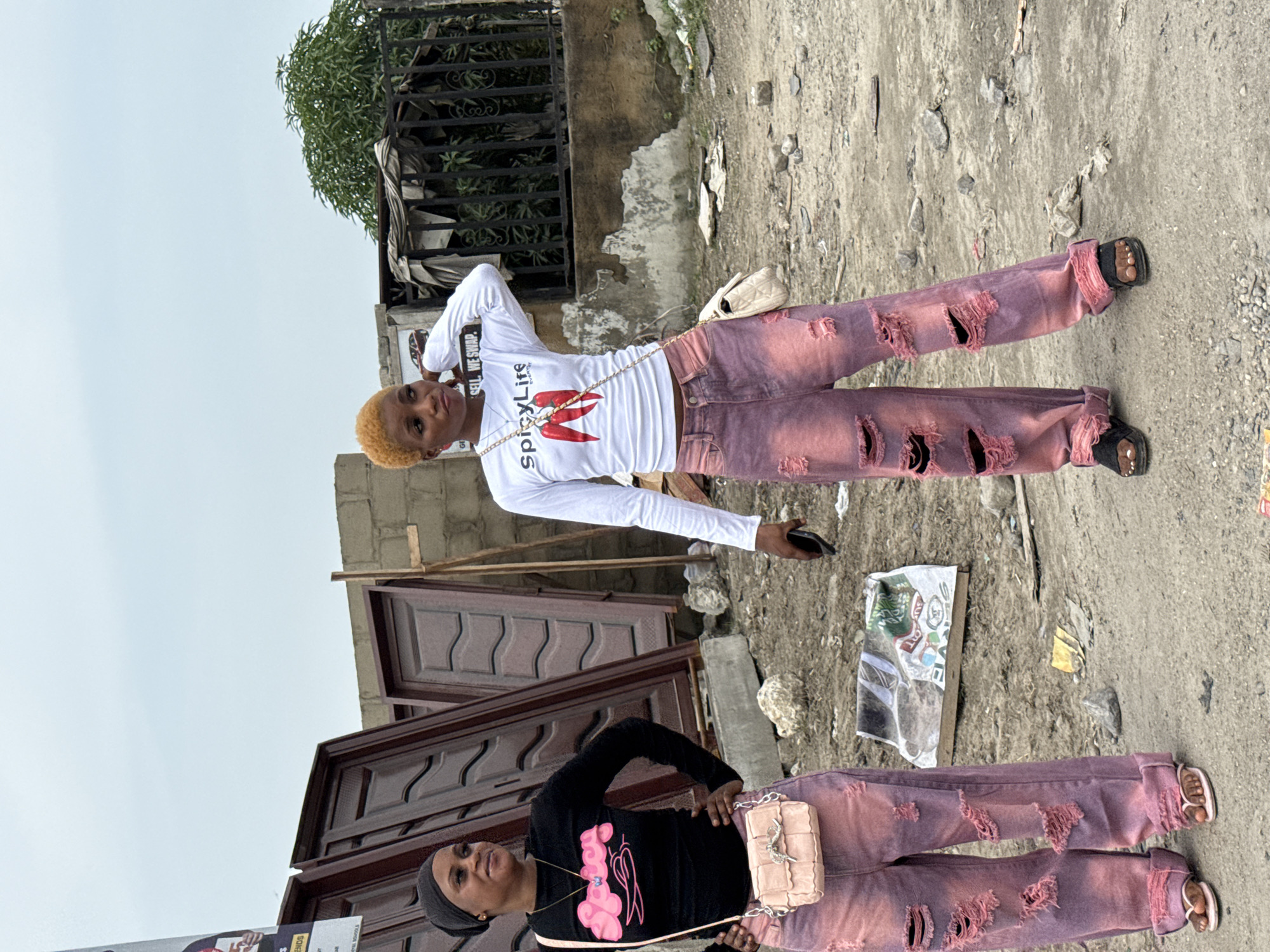 Two women stand on cracked pavement in Ado, Nigeria