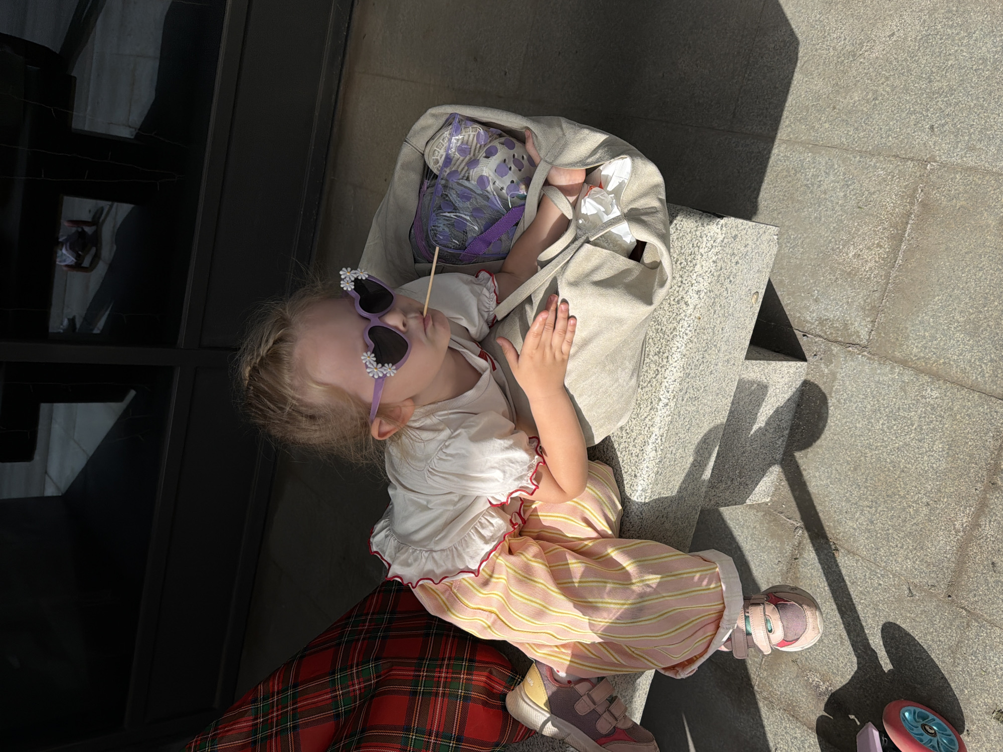 Child in decorative sunglasses sits outdoors in Saratov