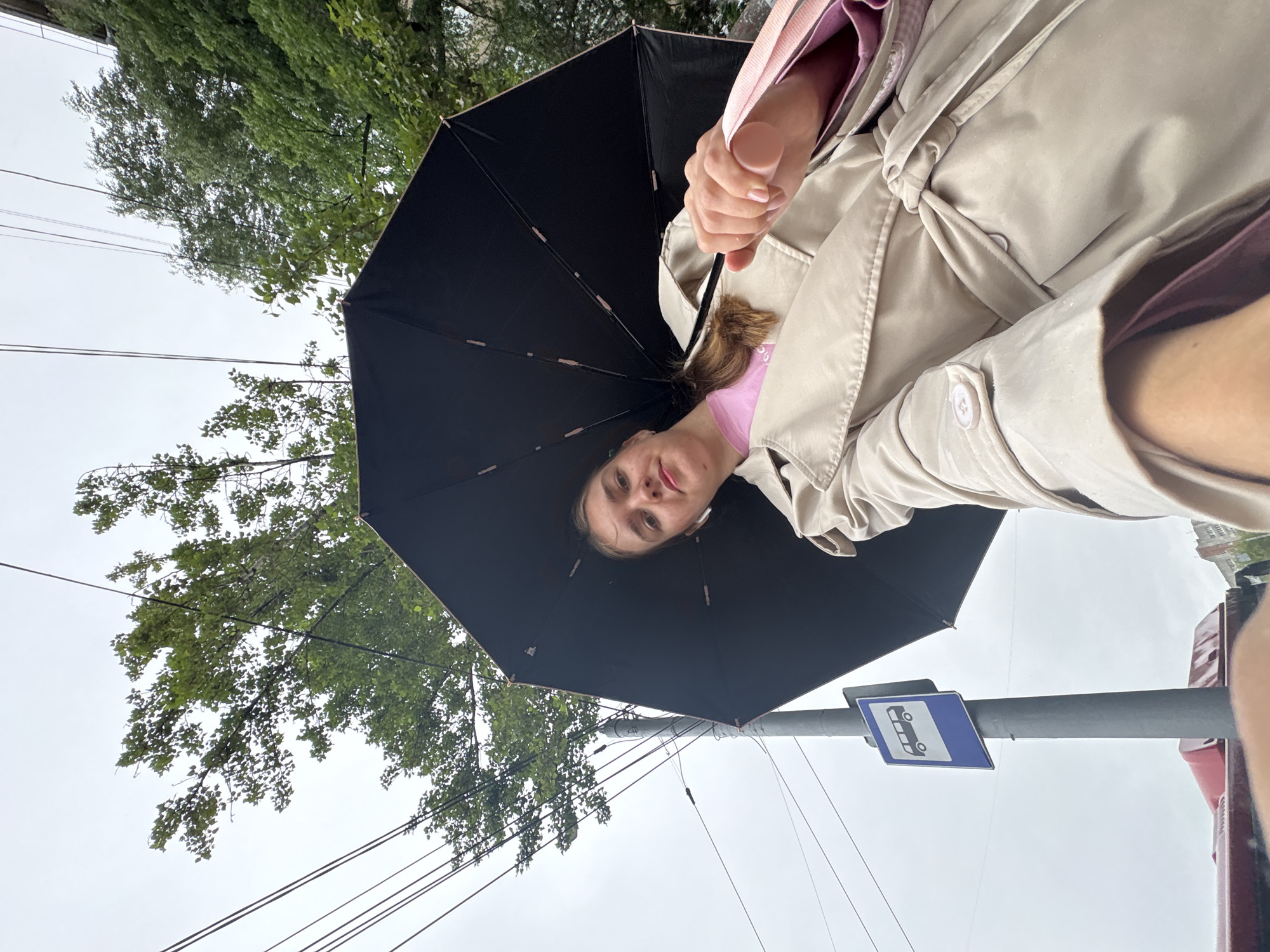 Waiting under an umbrella at a Perm bus stop