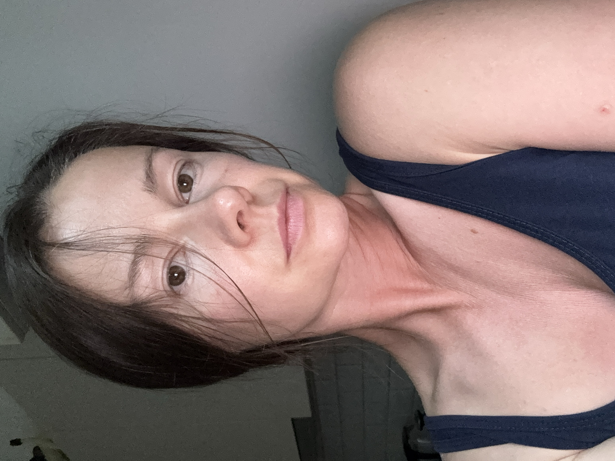 Close-up selfie in Riga, neutral gaze, hair across face.