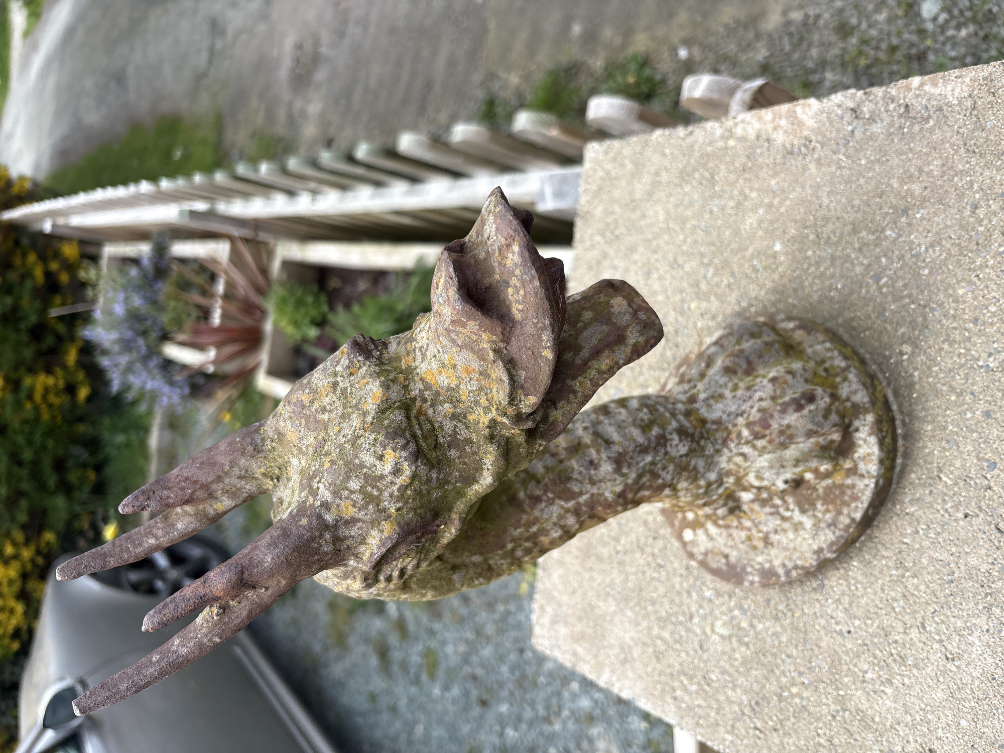 Weathered metal bird ornament spotted on concrete pillar in Minsterley