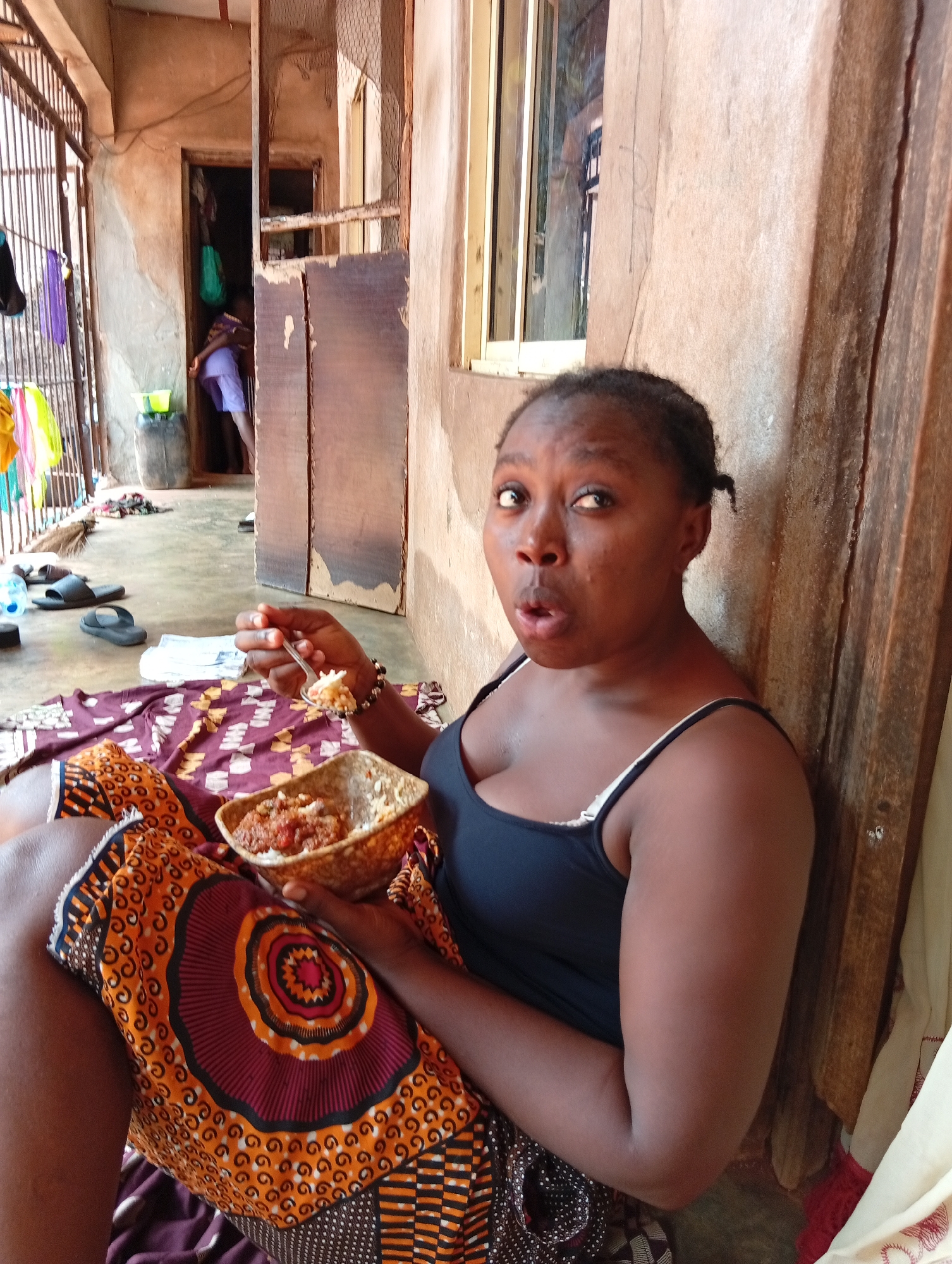 Woman shows surprised expression while eating in Ogidi, Nigeria