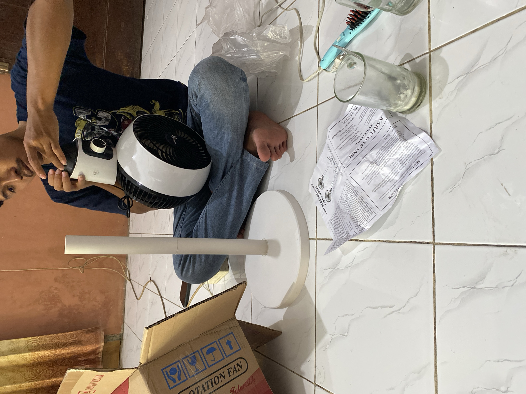 Man assembles fan, rests on floor in Madiun home