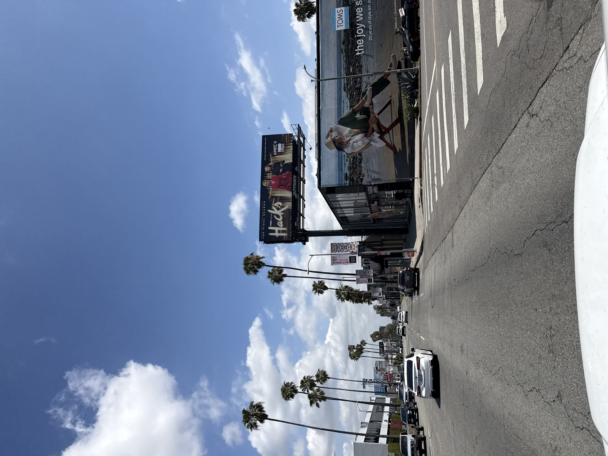 Palm-lined LA street scene with billboards and traffic