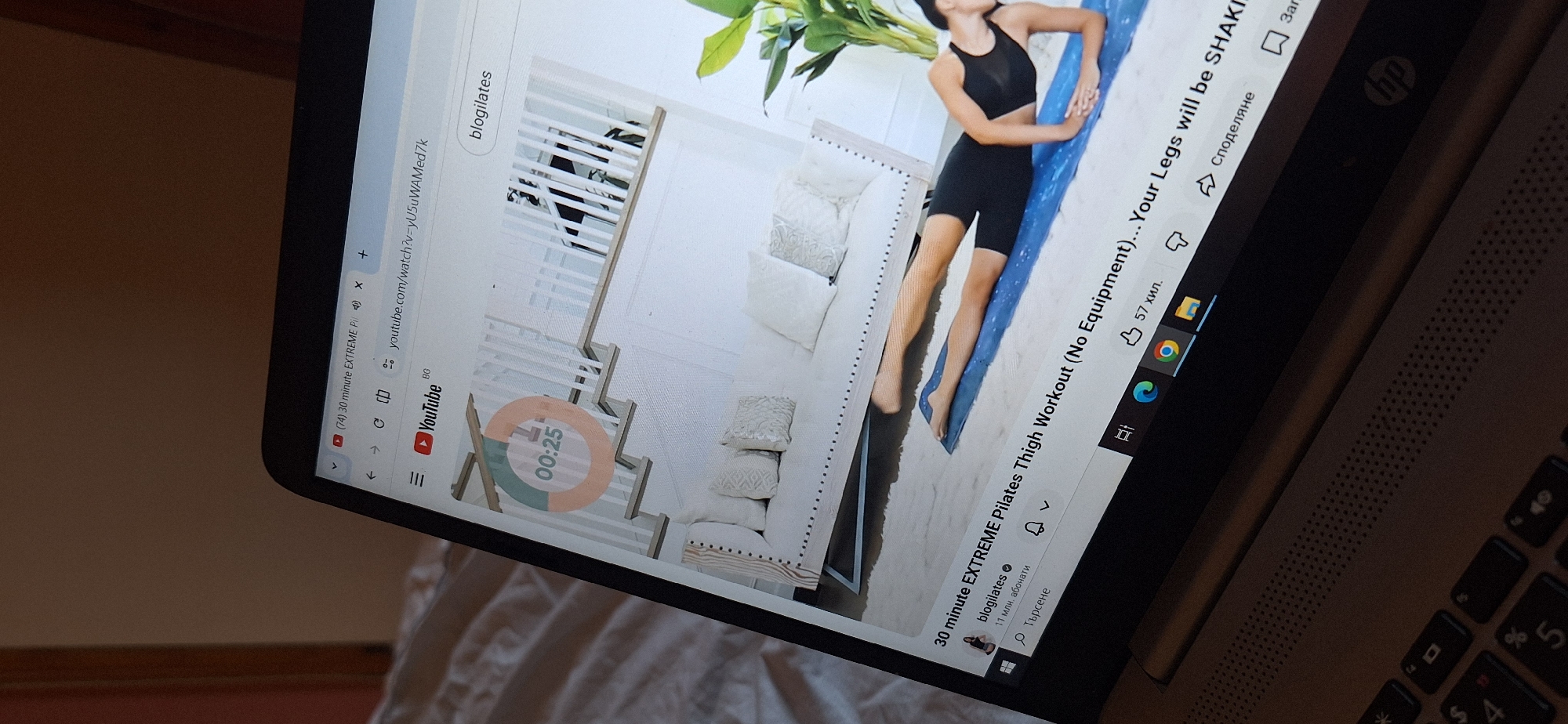 At-home Pilates session with YouTube workout playing on laptop