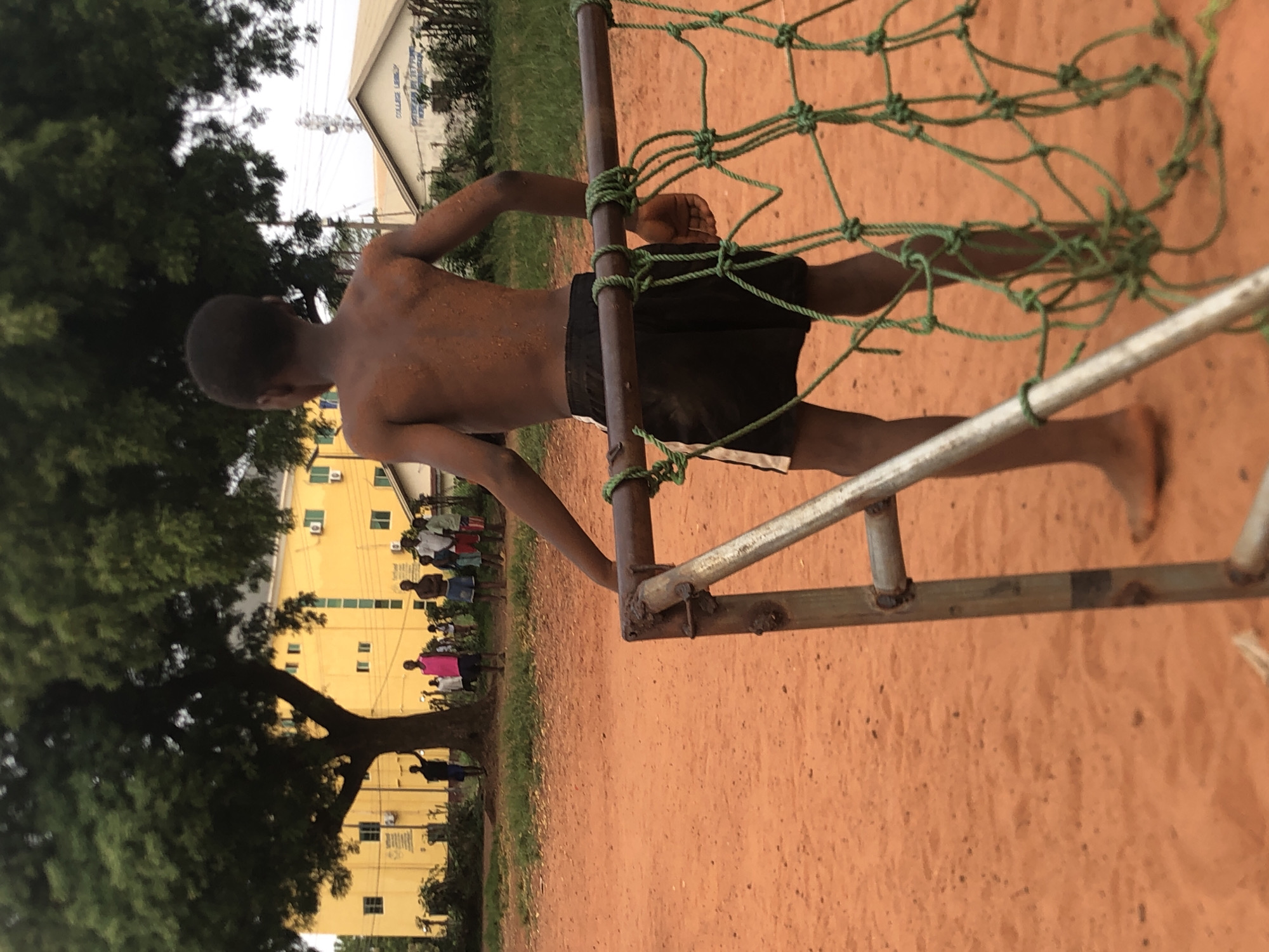 Young men play informal soccer on dirt field in Nigeria