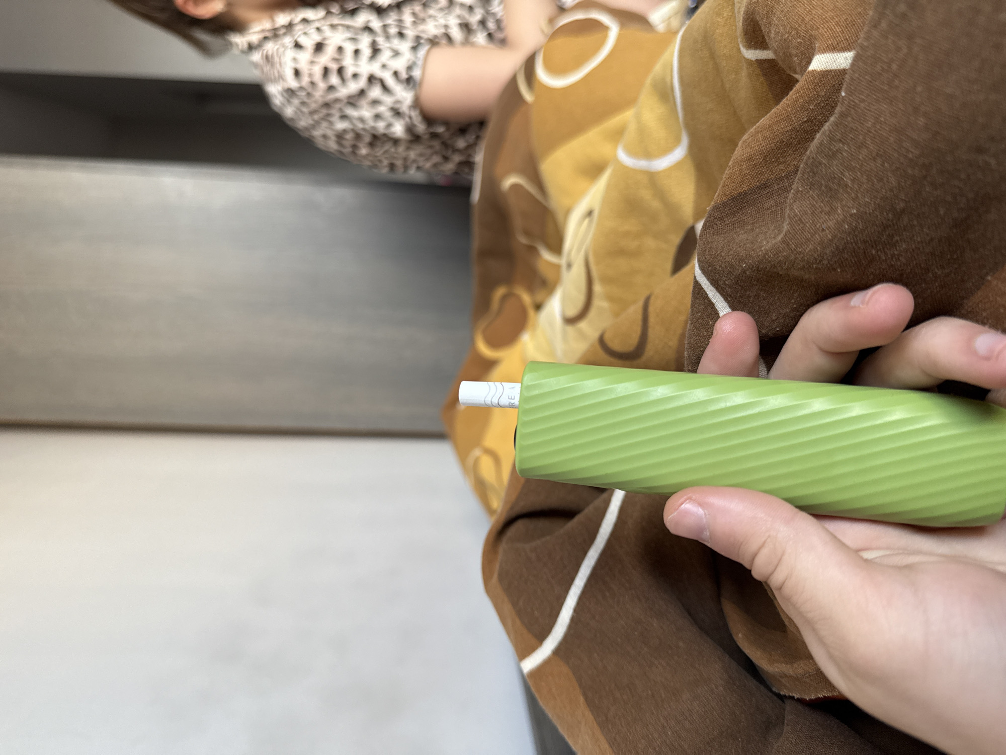 Person uses e-cigarette on blanket with child present