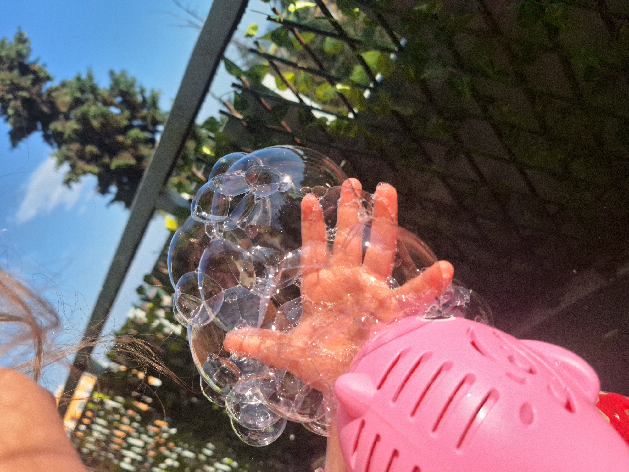 Child plays with pink pig bubble machine outdoors