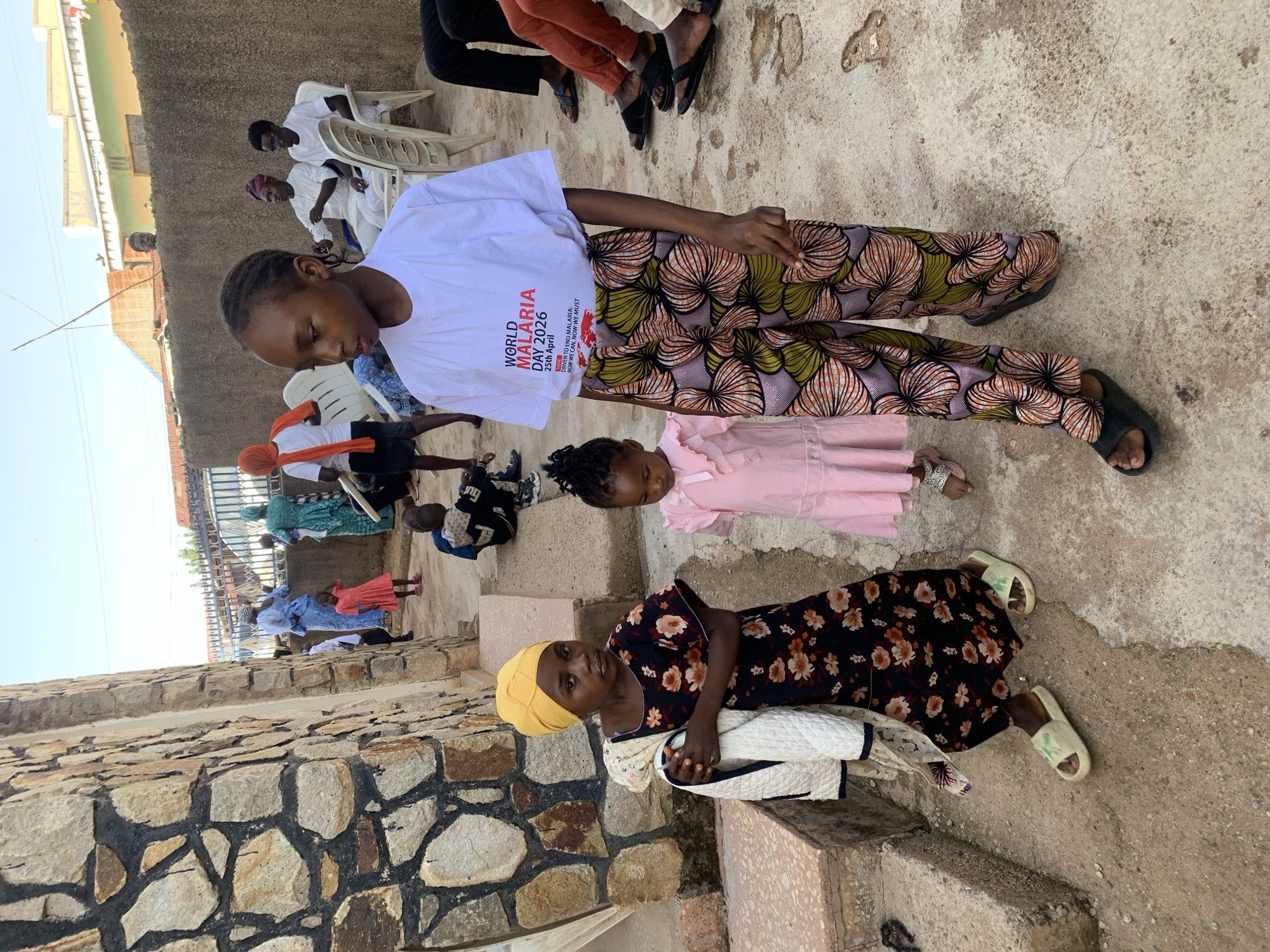 Community gathering at stone building in Jos, Nigeria