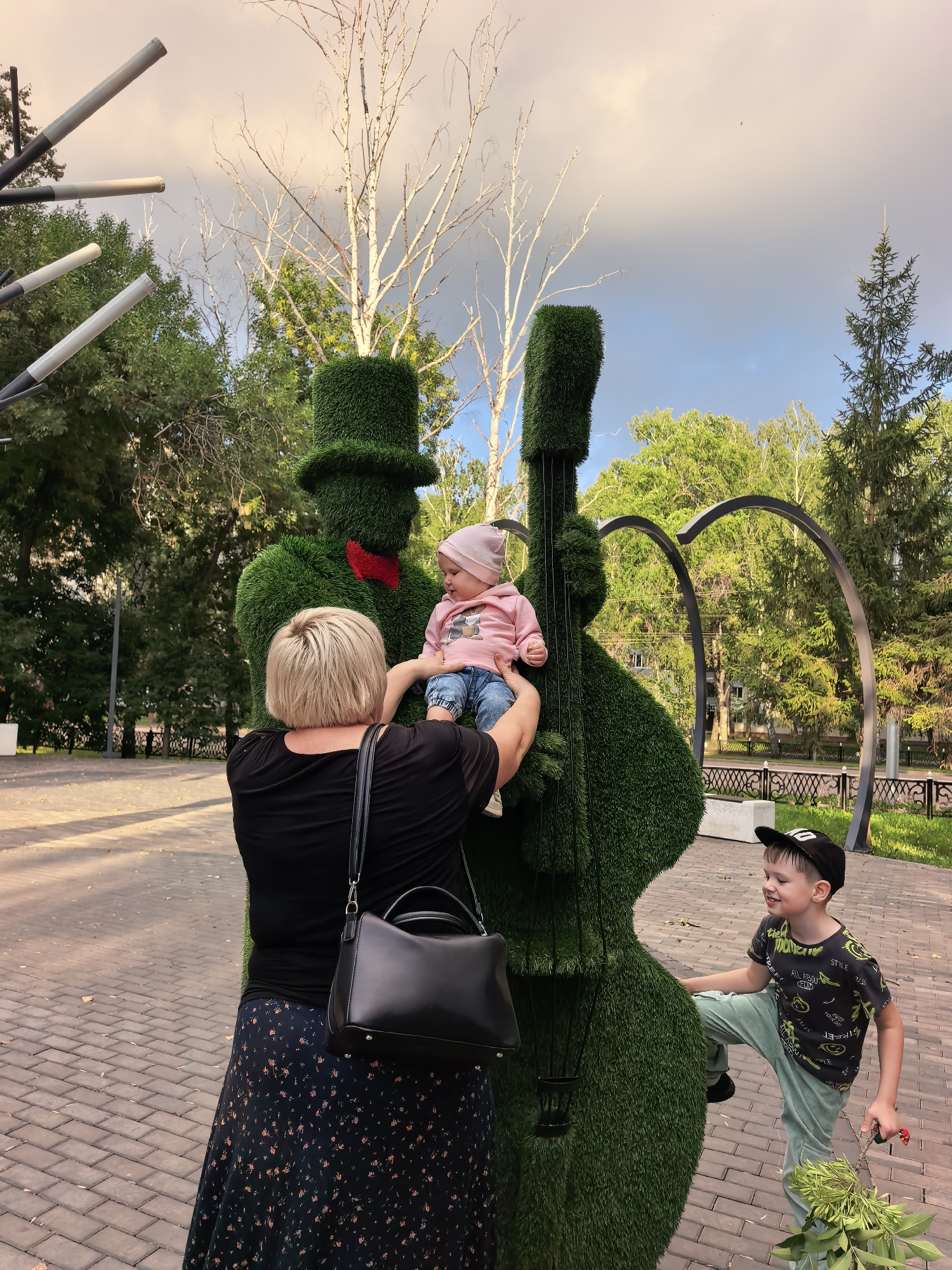 Afternoon at a Sterlitamak park with topiary musicians and a toddler