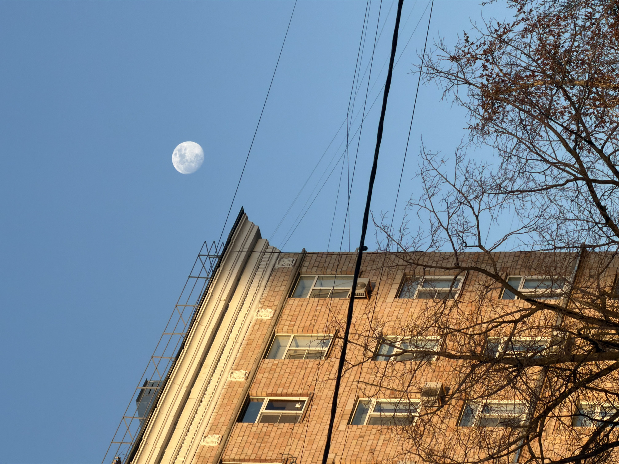 Moscow apartment building photographed under clear daytime sky with moon