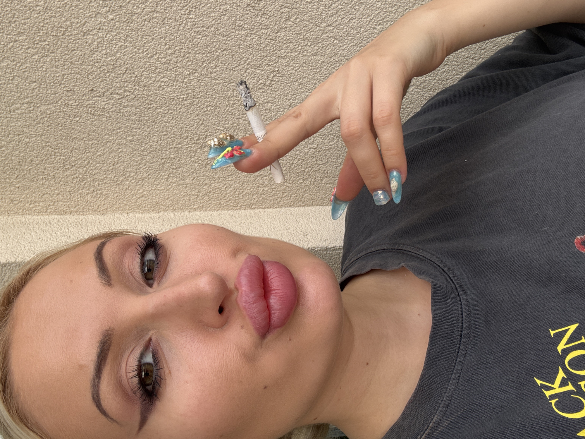 Close-up portrait with cigarette, bold makeup, and sculpted nails.
