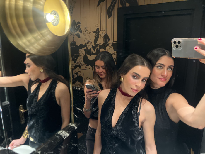 Three women take mirror selfies in Paris bathroom