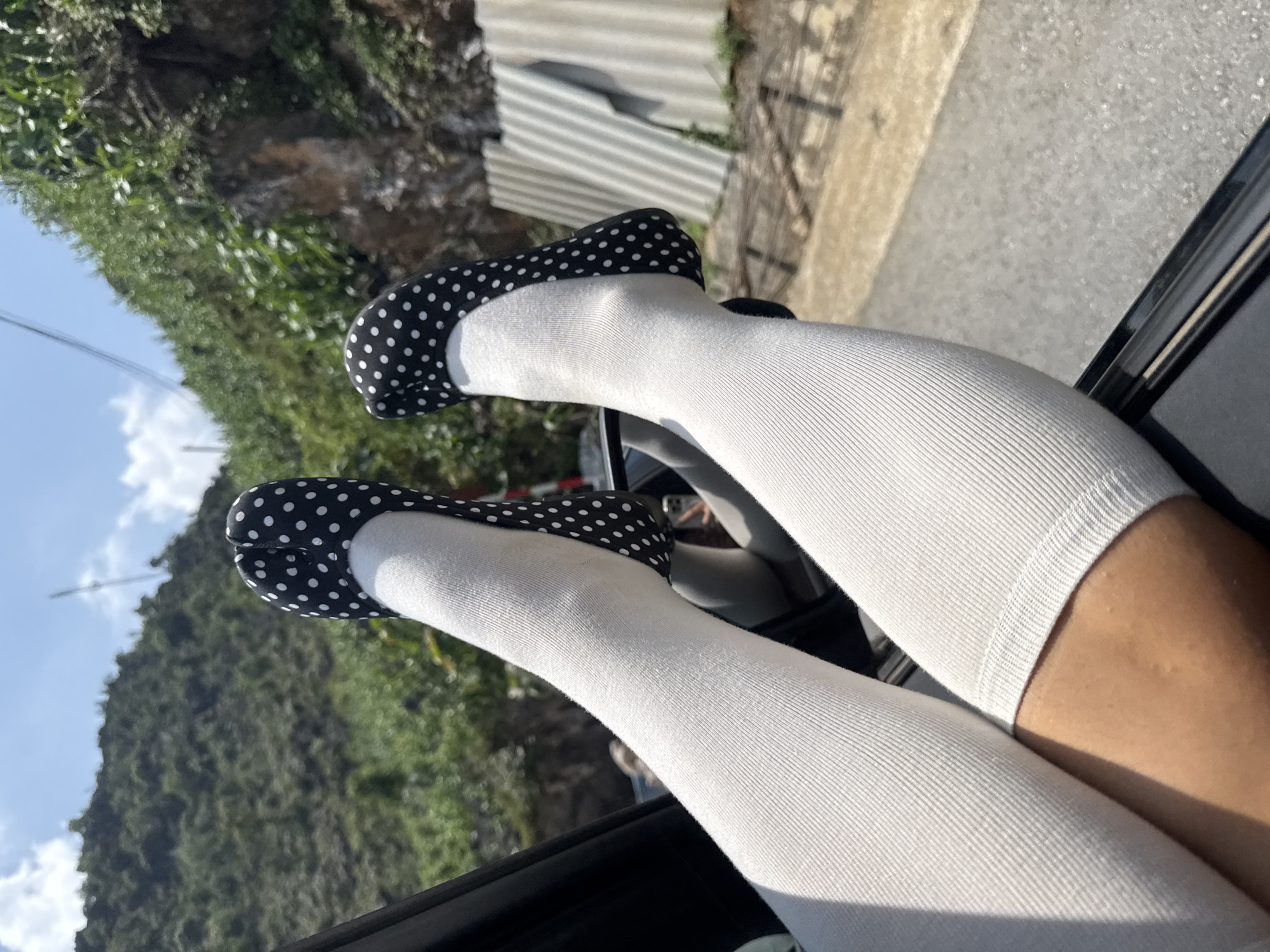 Person rests legs from car window in rural Vietnam
