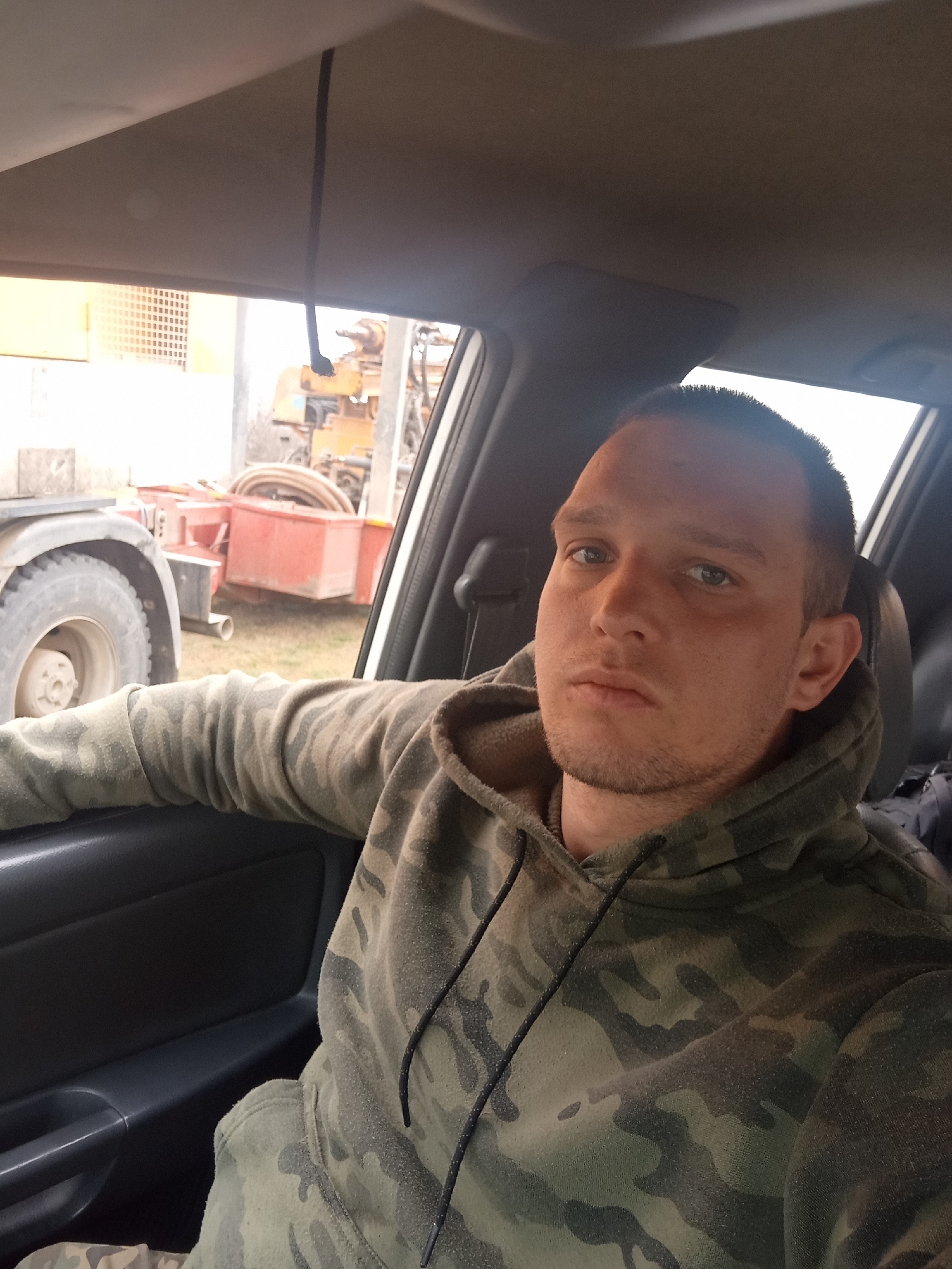 Man in camouflage hoodie sits near heavy machinery Bulgaria