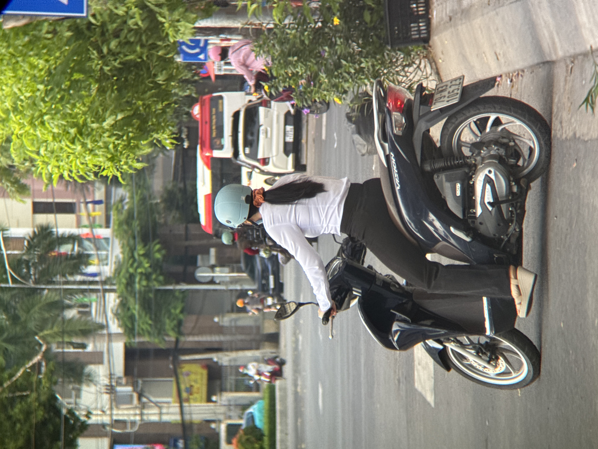 Everyday street life in Nha Trang: scooters, riders, and tree trimming