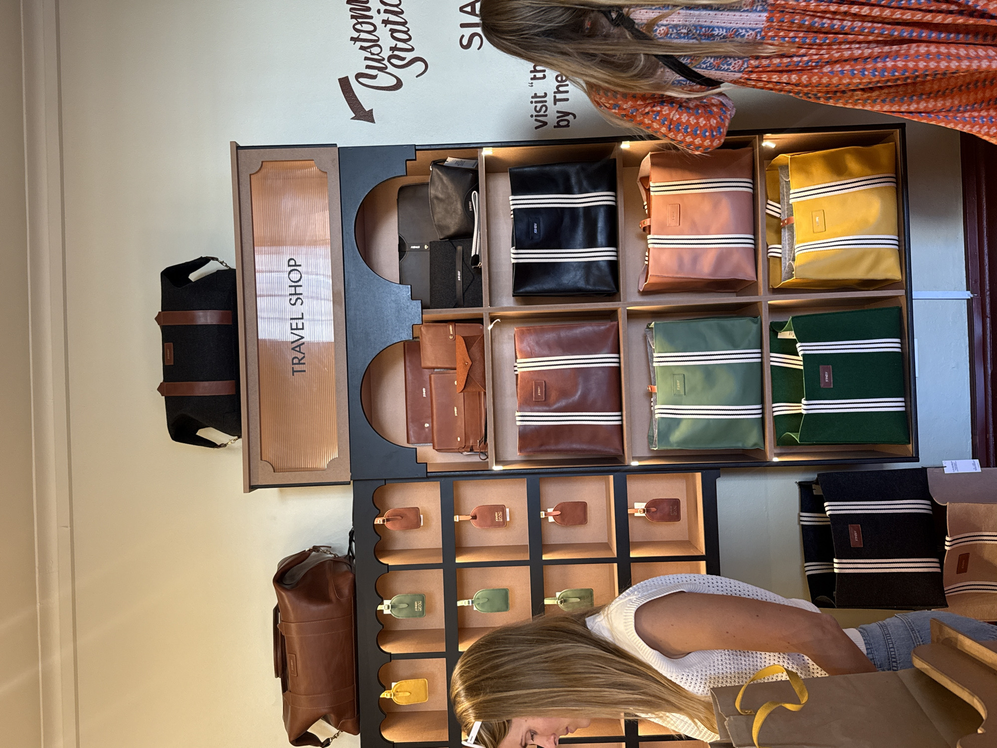 Woman browses luggage tags at travel accessories shop