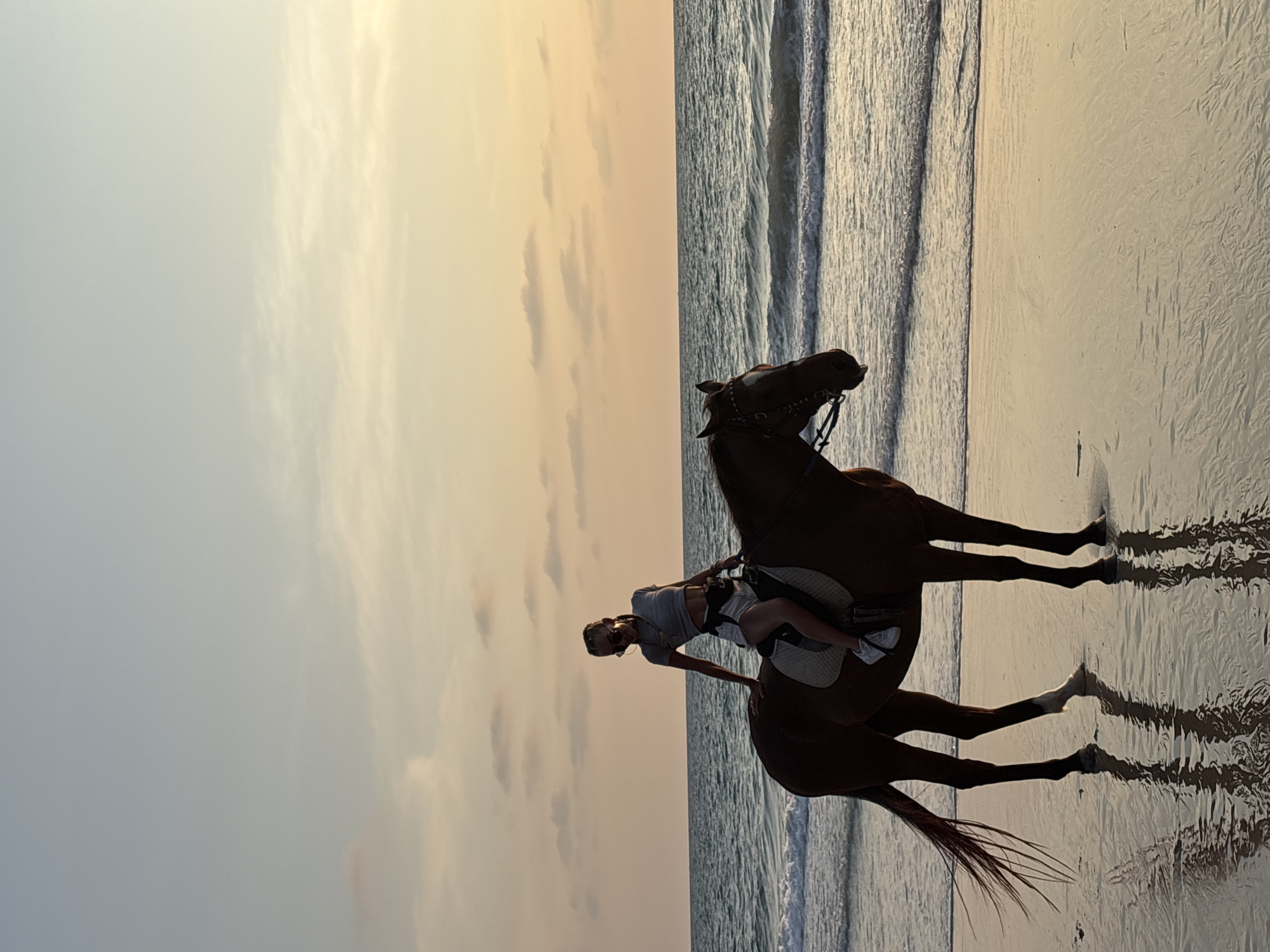 Woman enjoys sunset horseback ride on Thai beach