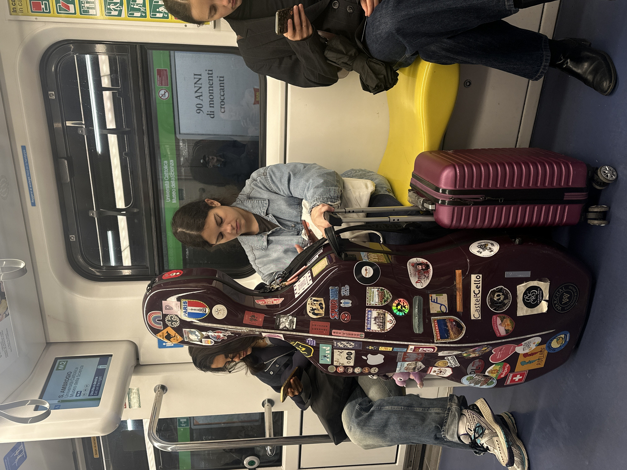 Woman sleeps beside cello case on Milan Metro train