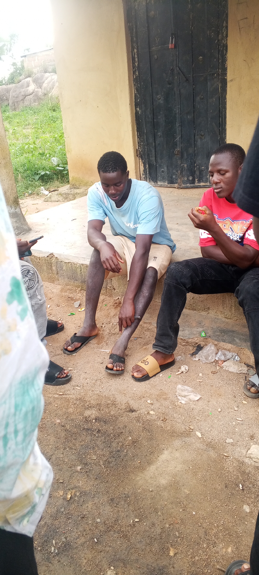 Small groups gathered outside modest structures in an informal setting