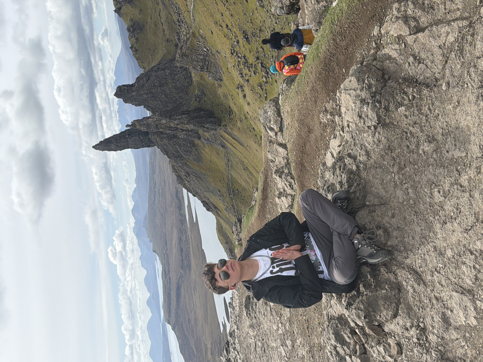Hiker rests on rocky outcrop near Portree