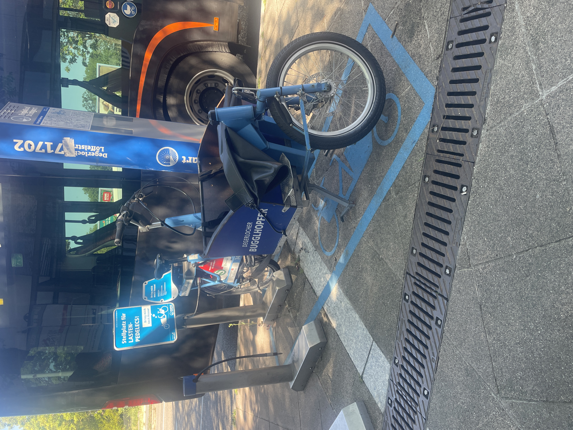 Blue cargo bike parked at a designated sidewalk stop