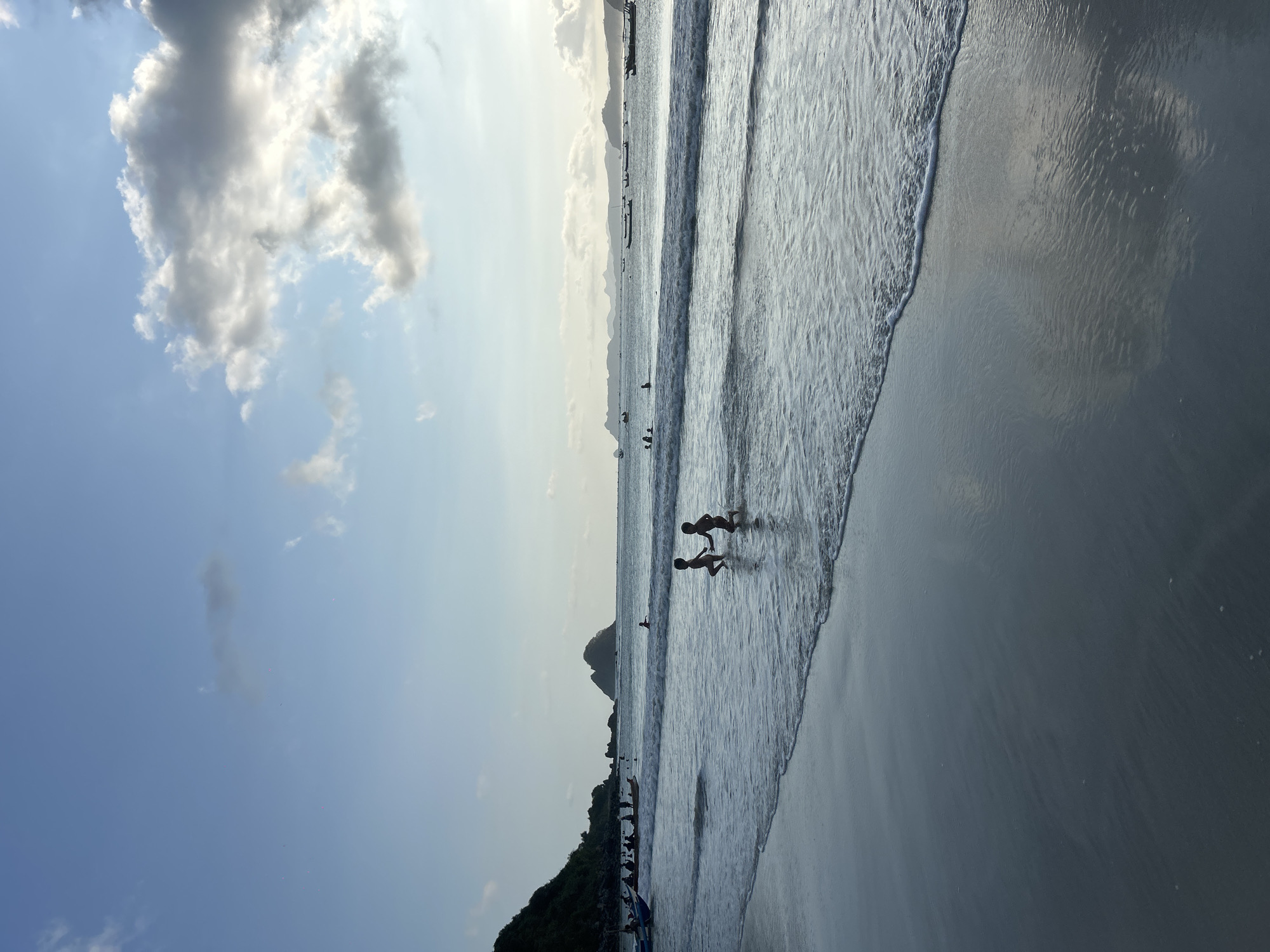 Quiet morning on Selongbelanak beach, figure wading into calm surf