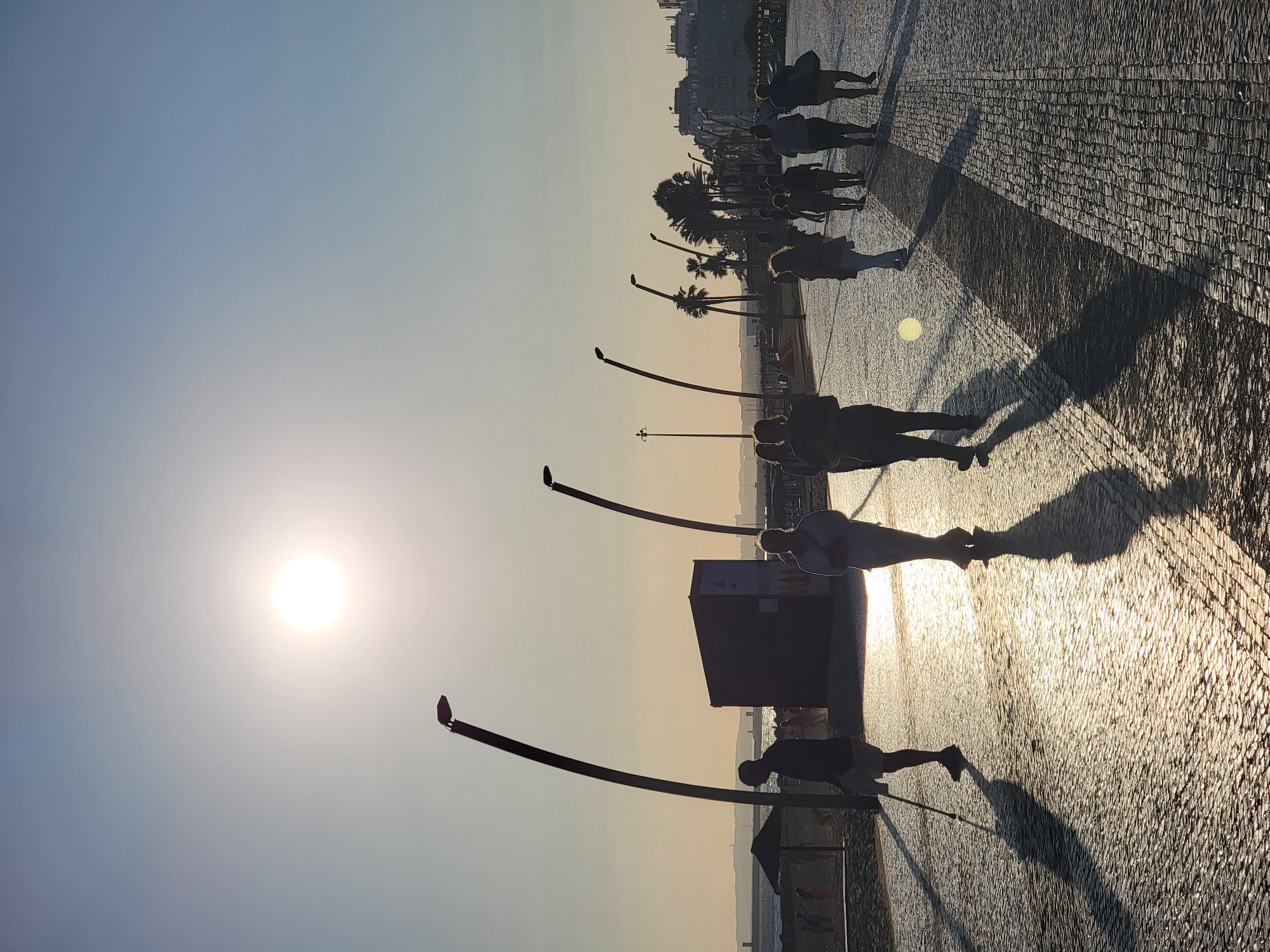 Sunset strolls and beach construction on Quarteira's promenade