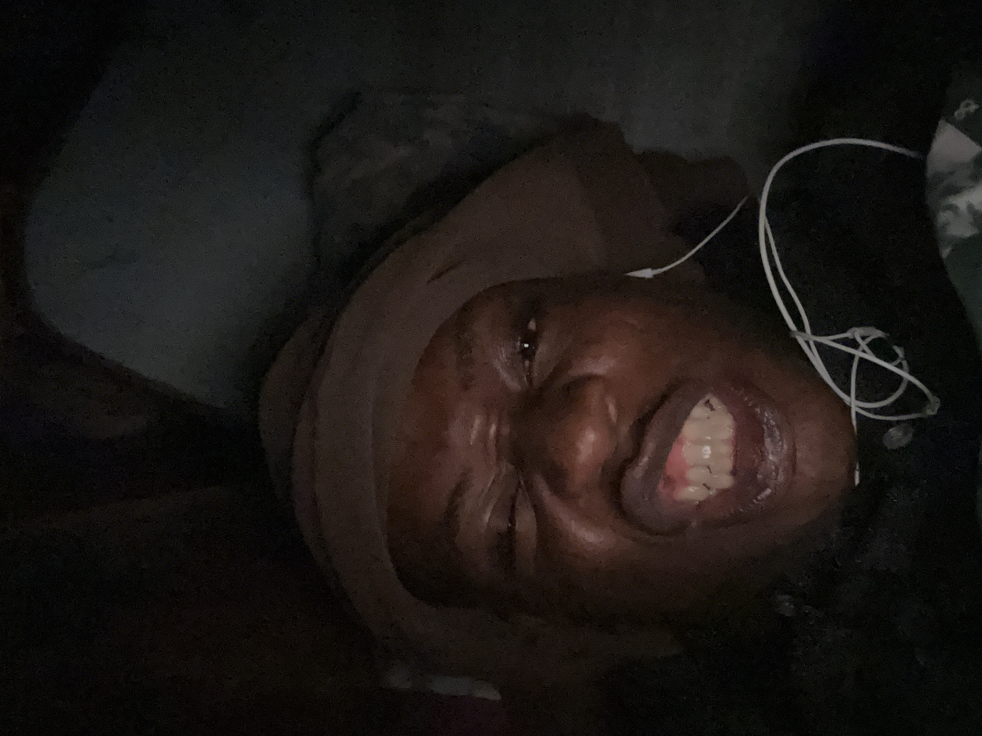 Person rests with earphones in dimly lit indoor setting