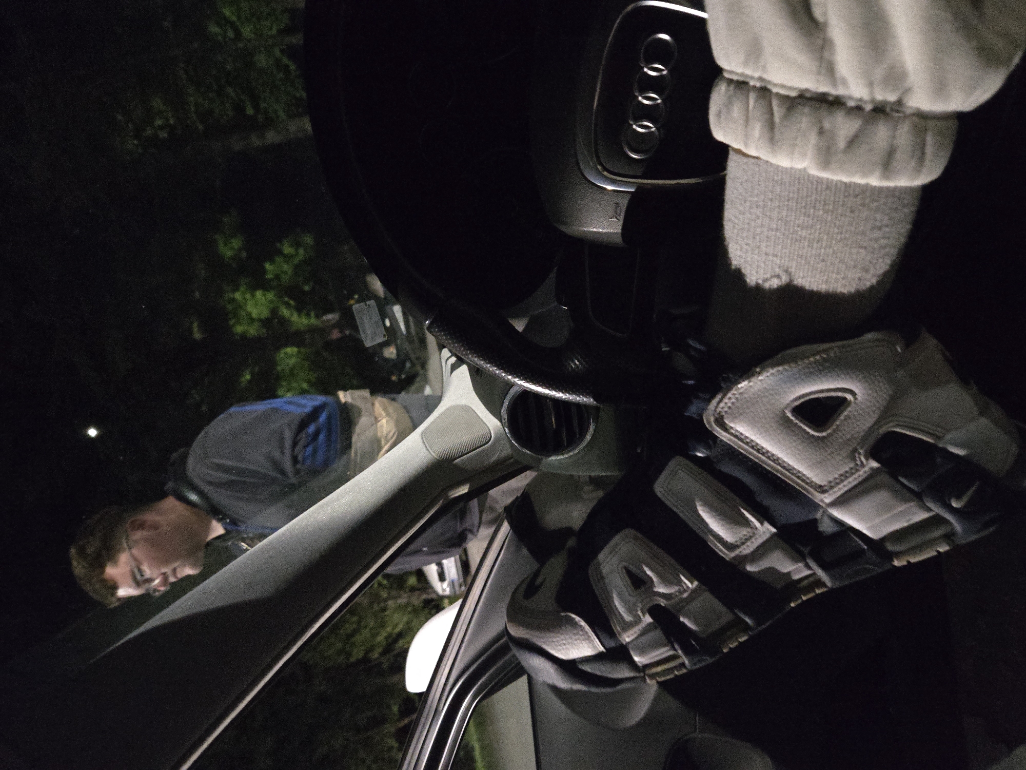 Driver rests leg on steering wheel in Audi at night