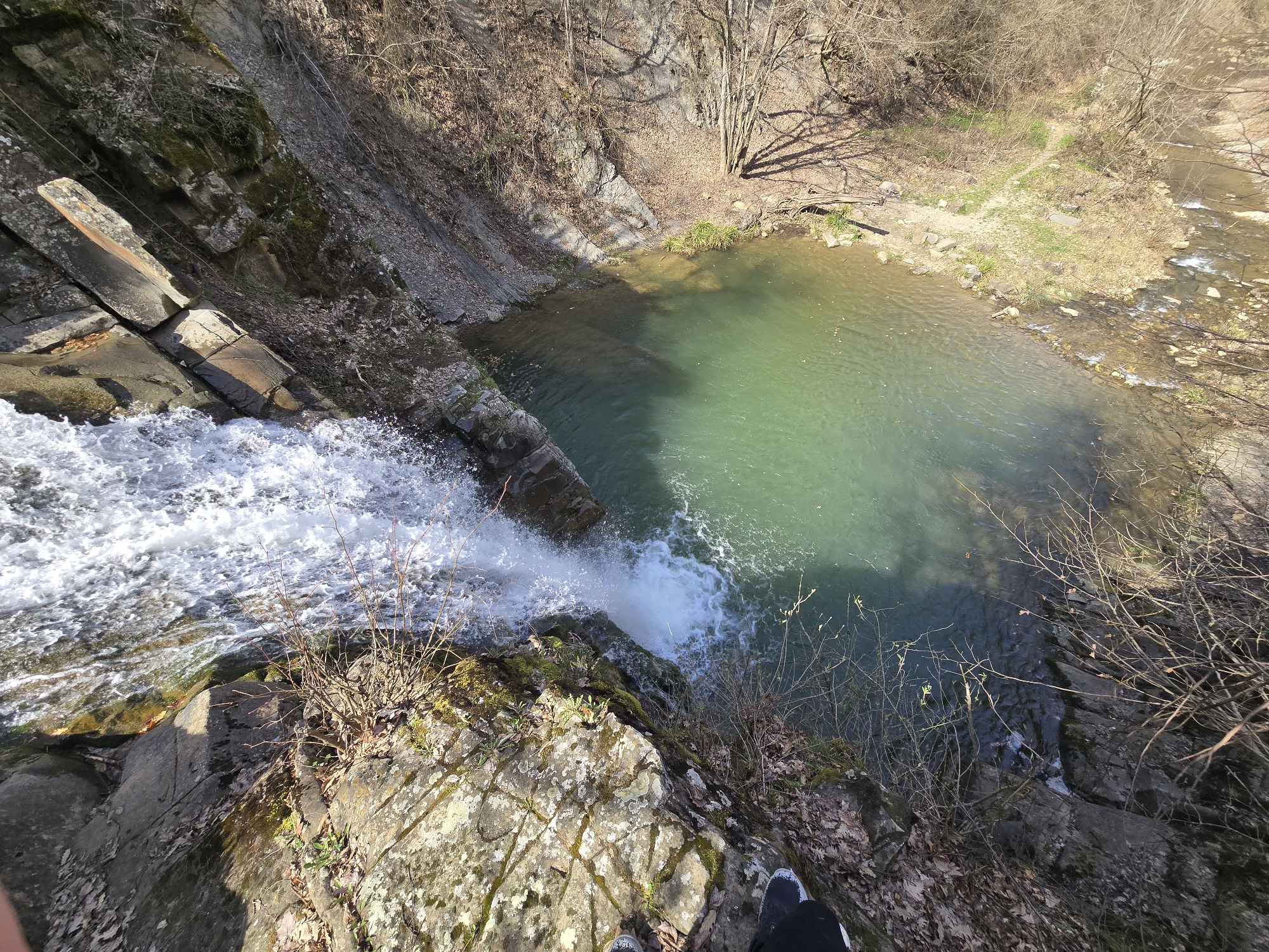 Witness documents waterfall cascading into lake amid rock formations
