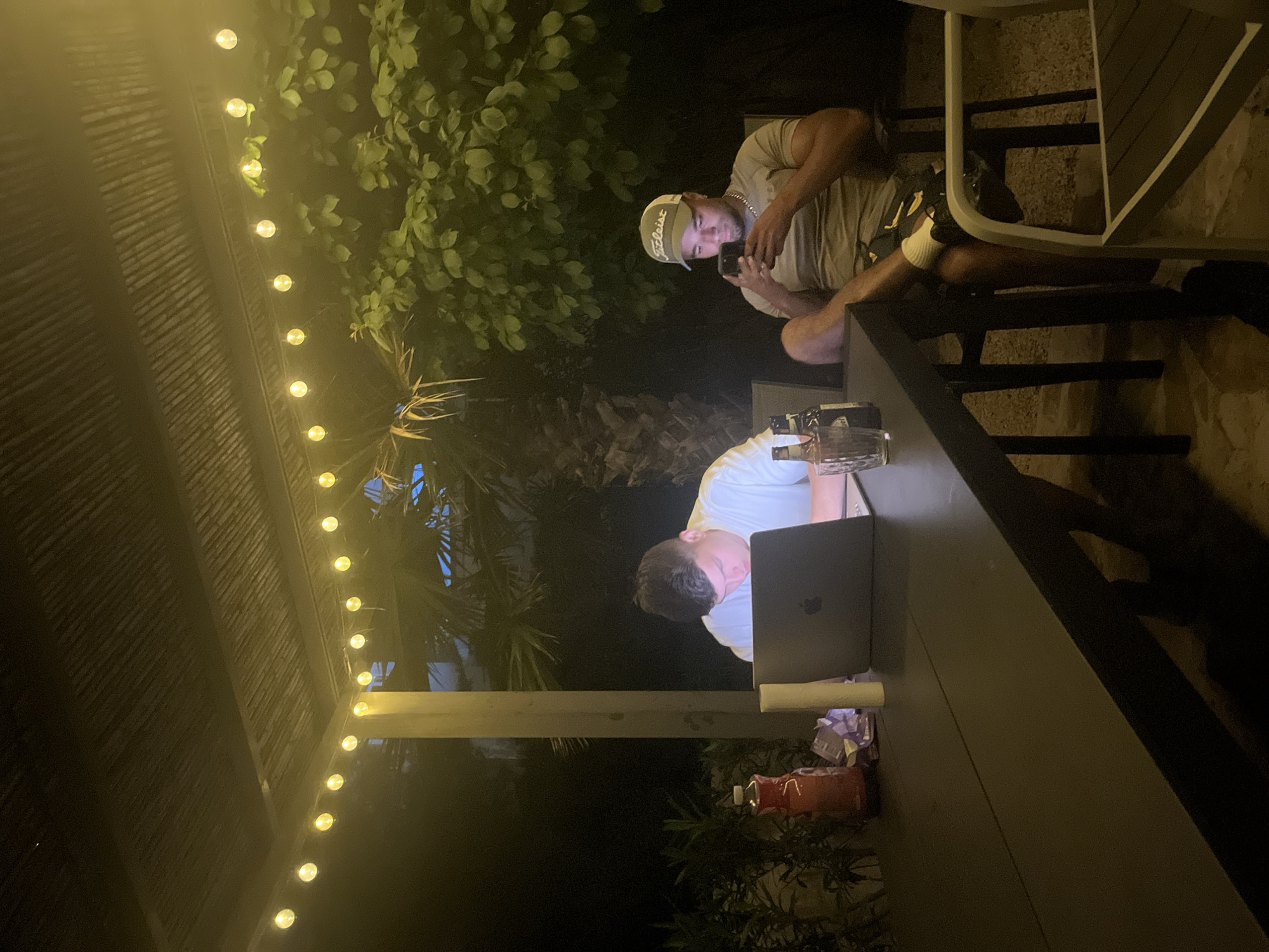 Three men gather at nighttime patio in Spanish coastal town