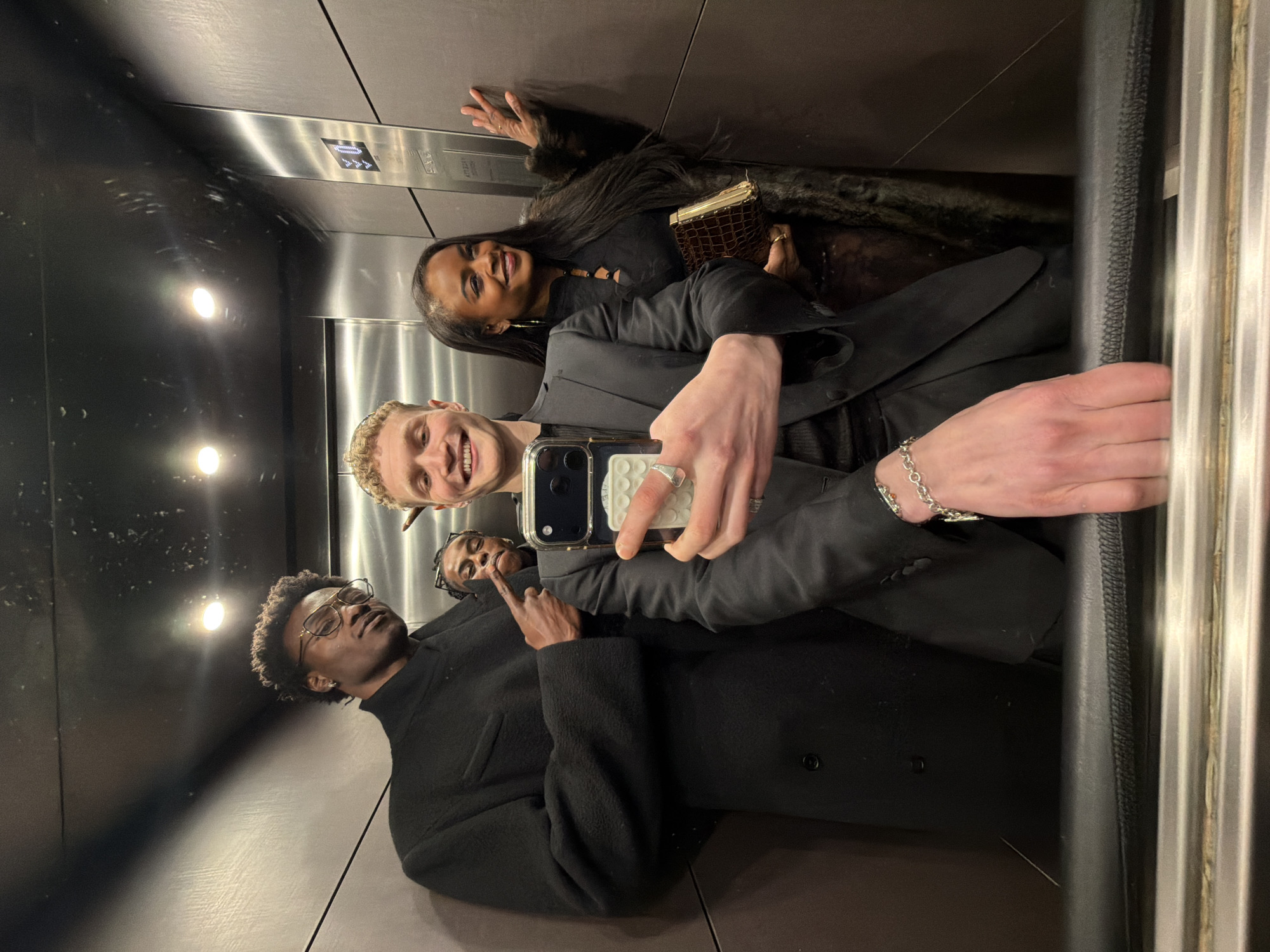 Four people take mirror selfie in London elevator