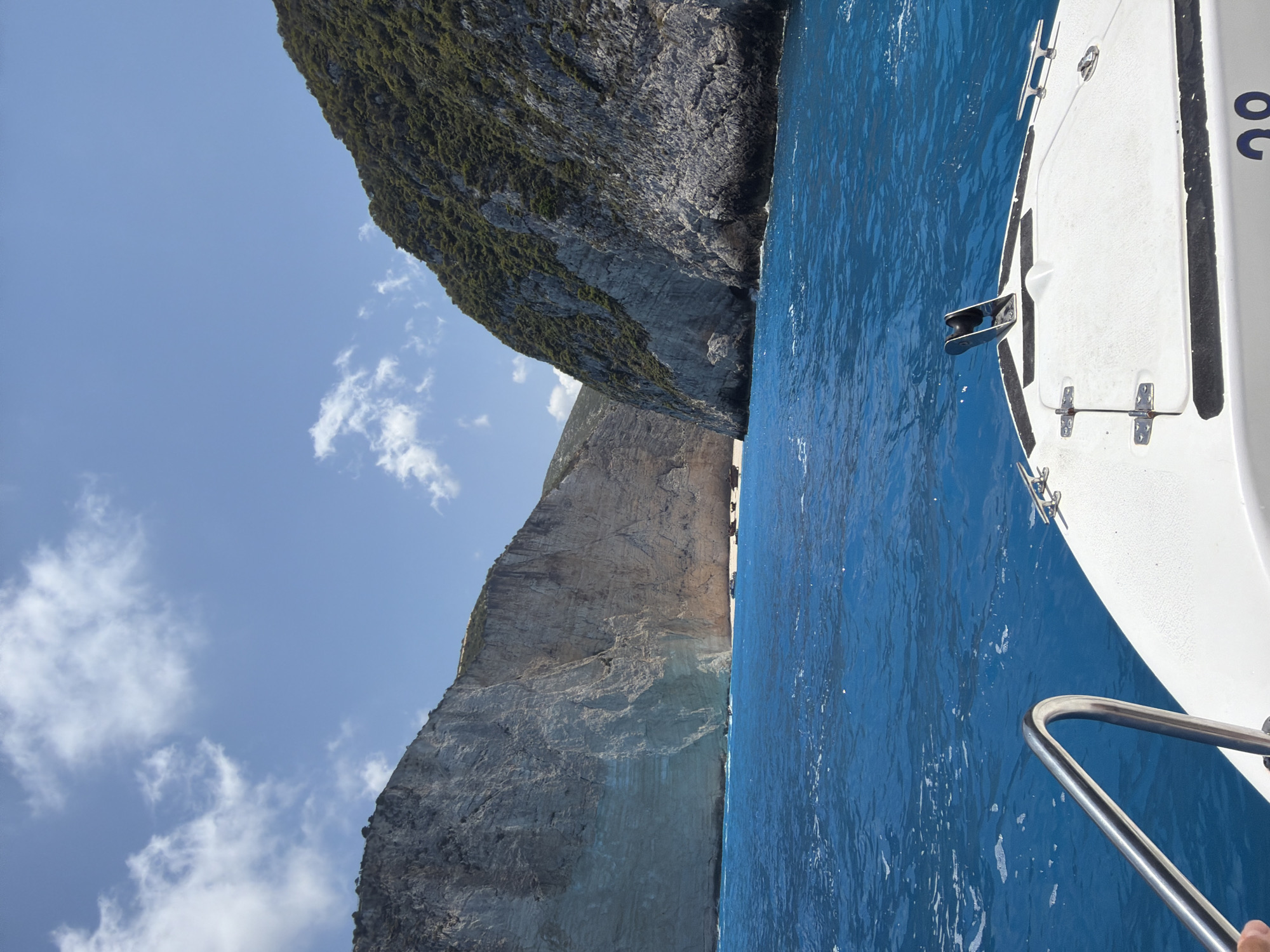 White boat cruises past dramatic cliffs on open ocean