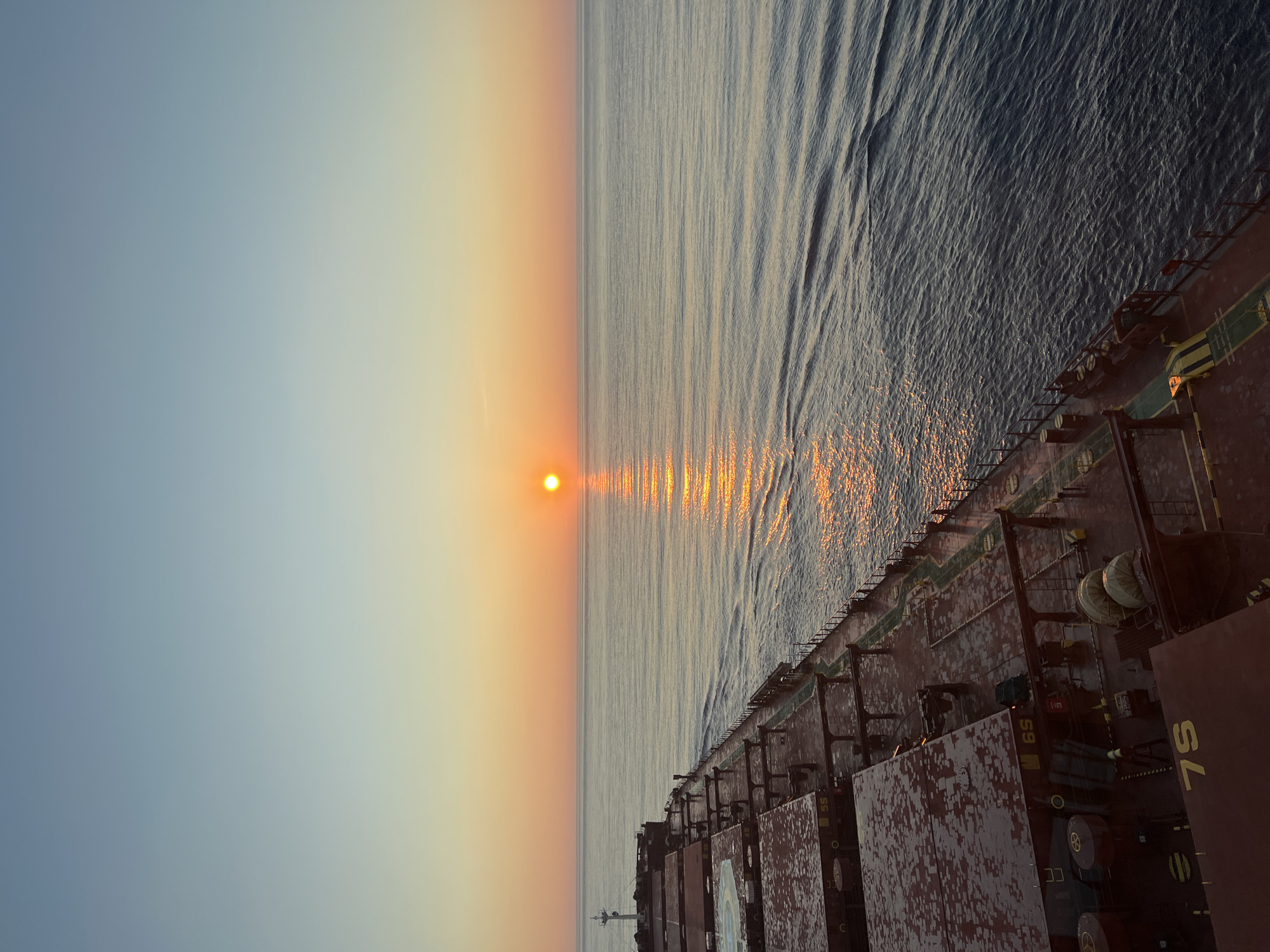 Cargo ship crosses open ocean at golden hour