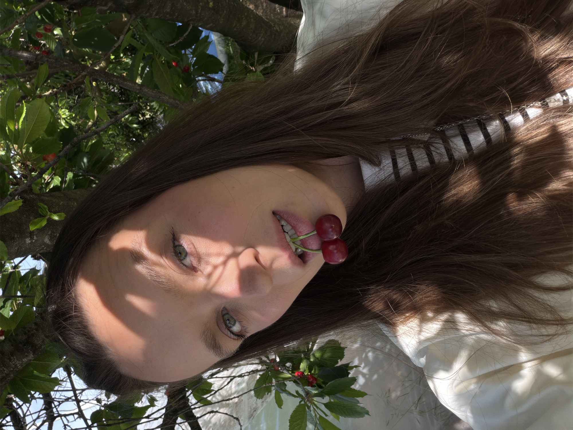 Woman photographed with cherries under fruit tree in Montenegro