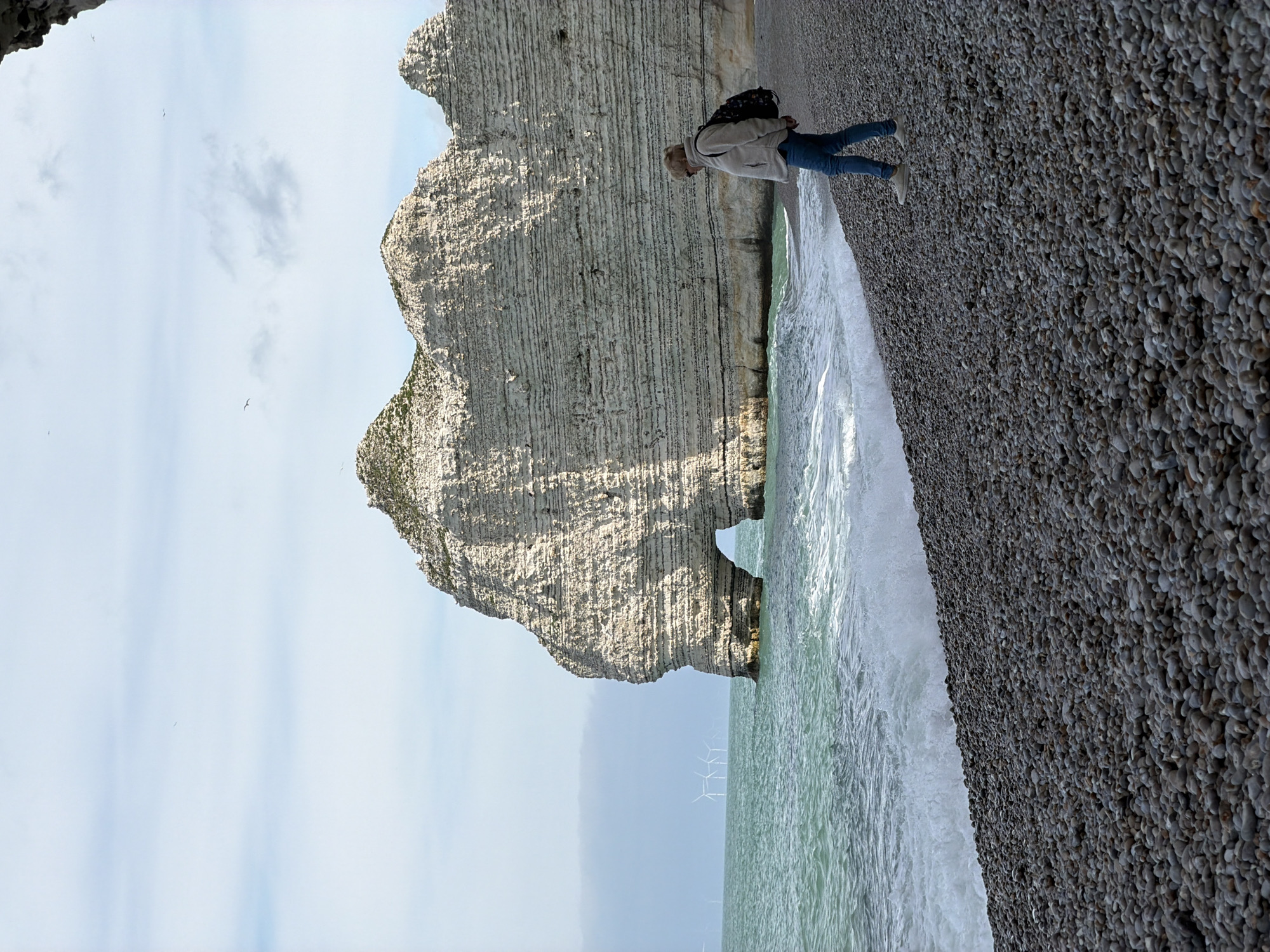 Woman relaxes on rocky beach near Étretat's famous cliffs