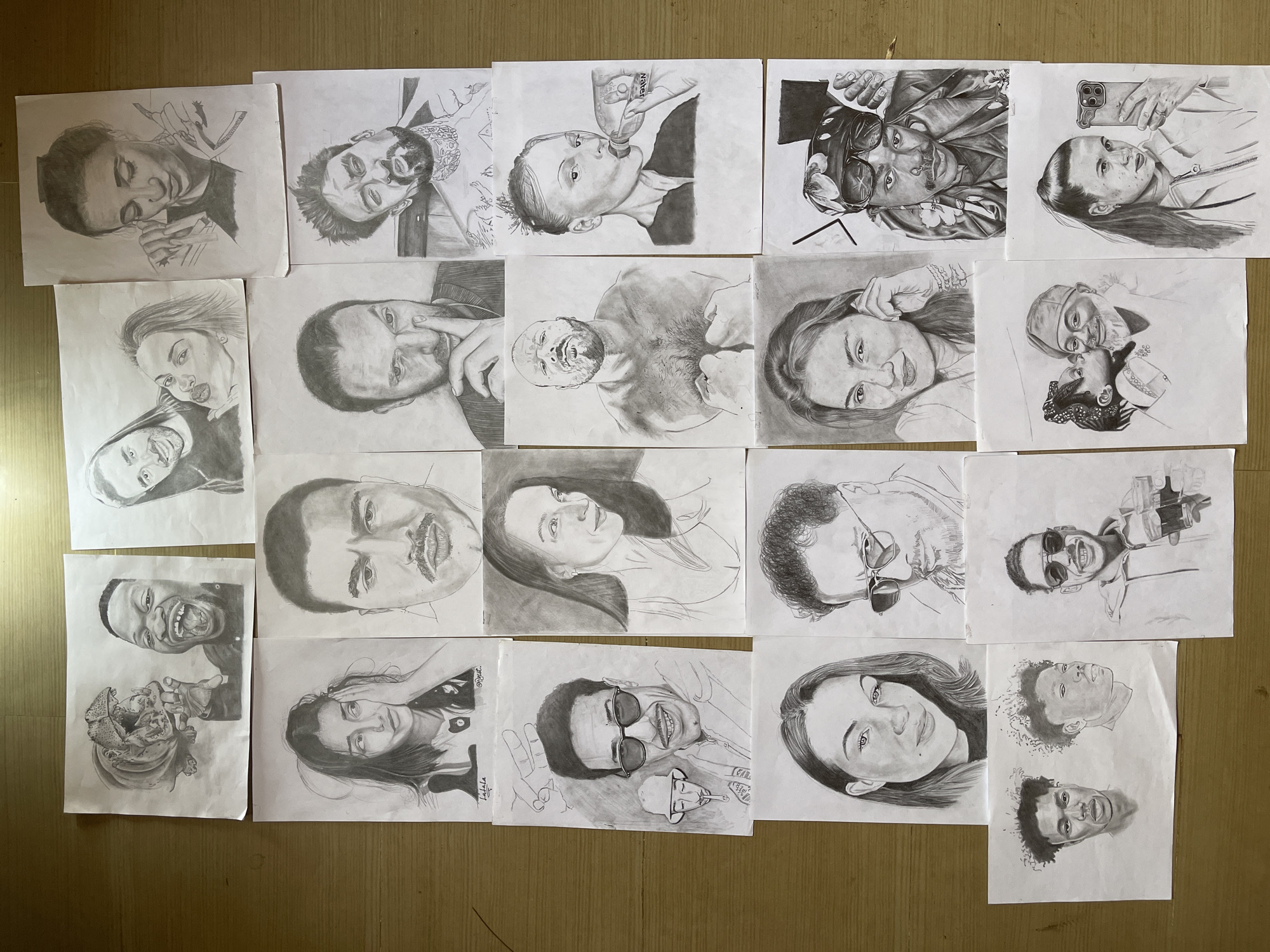 Artist displays portrait sketch collection on wooden floor in Jos