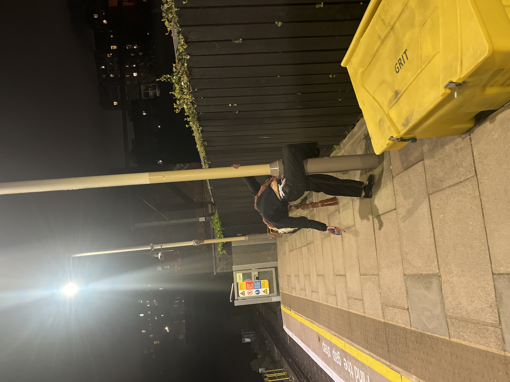 Person lies on London train platform using phone